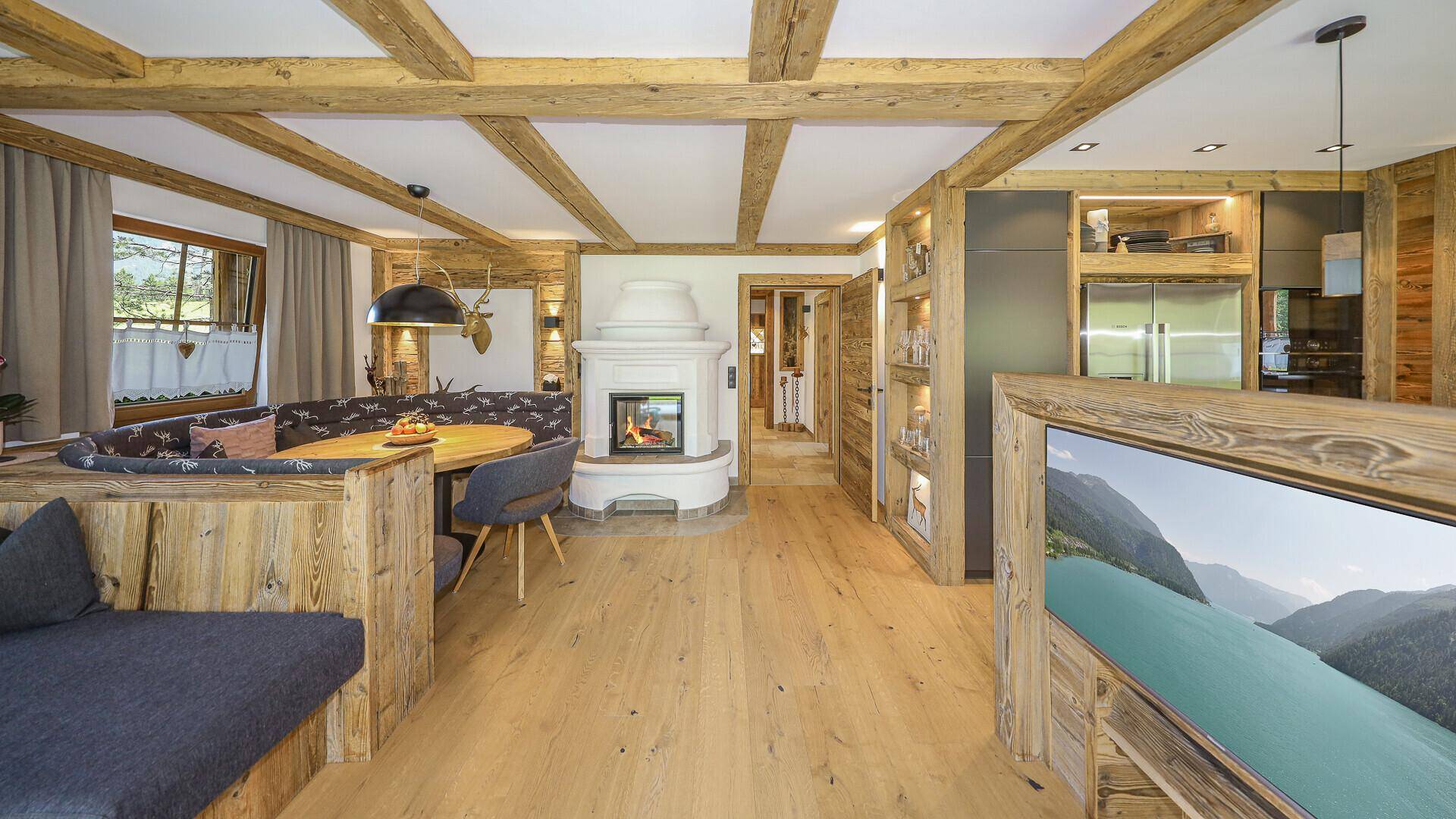 Offener Wohnbereich im Chalet-Stil mit Kamin, Holzelementen und integrierter Küchenzeile.