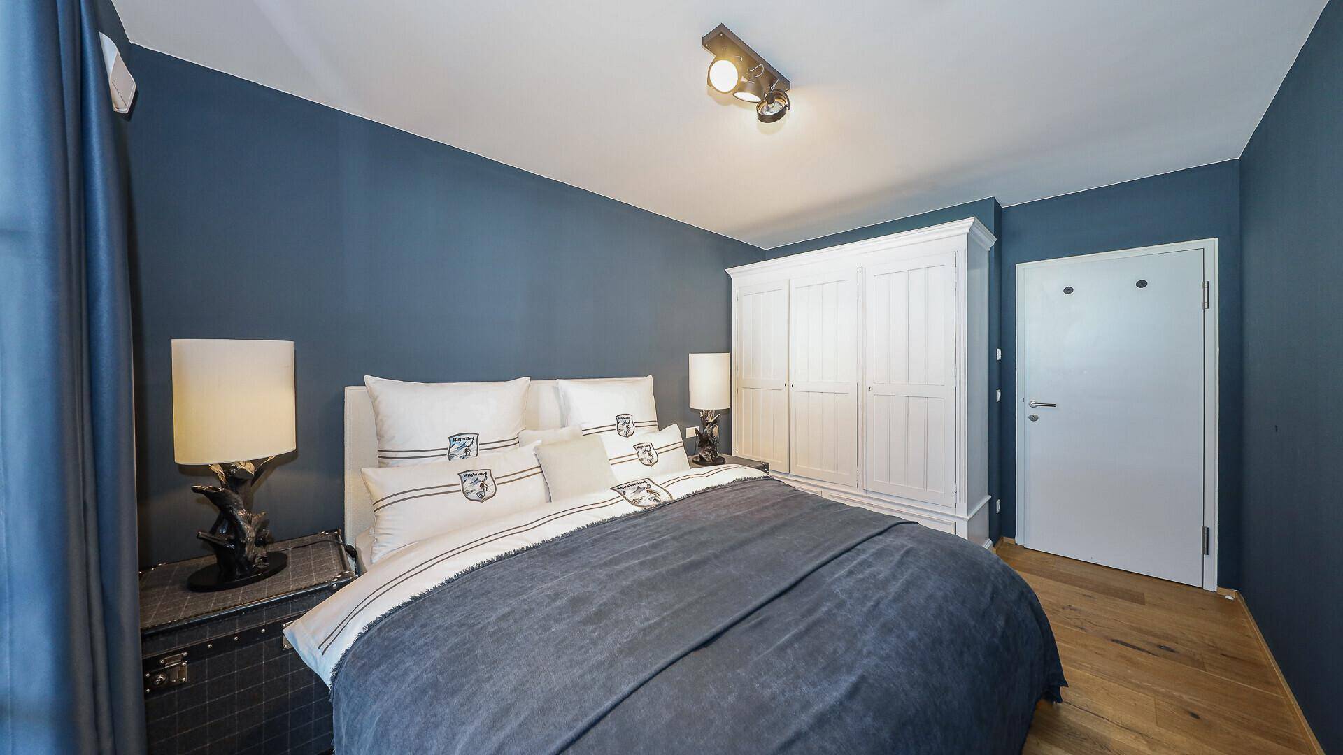 Komfortables Schlafzimmer mit großem Bett, weißem Kleiderschrank und Holzboden.