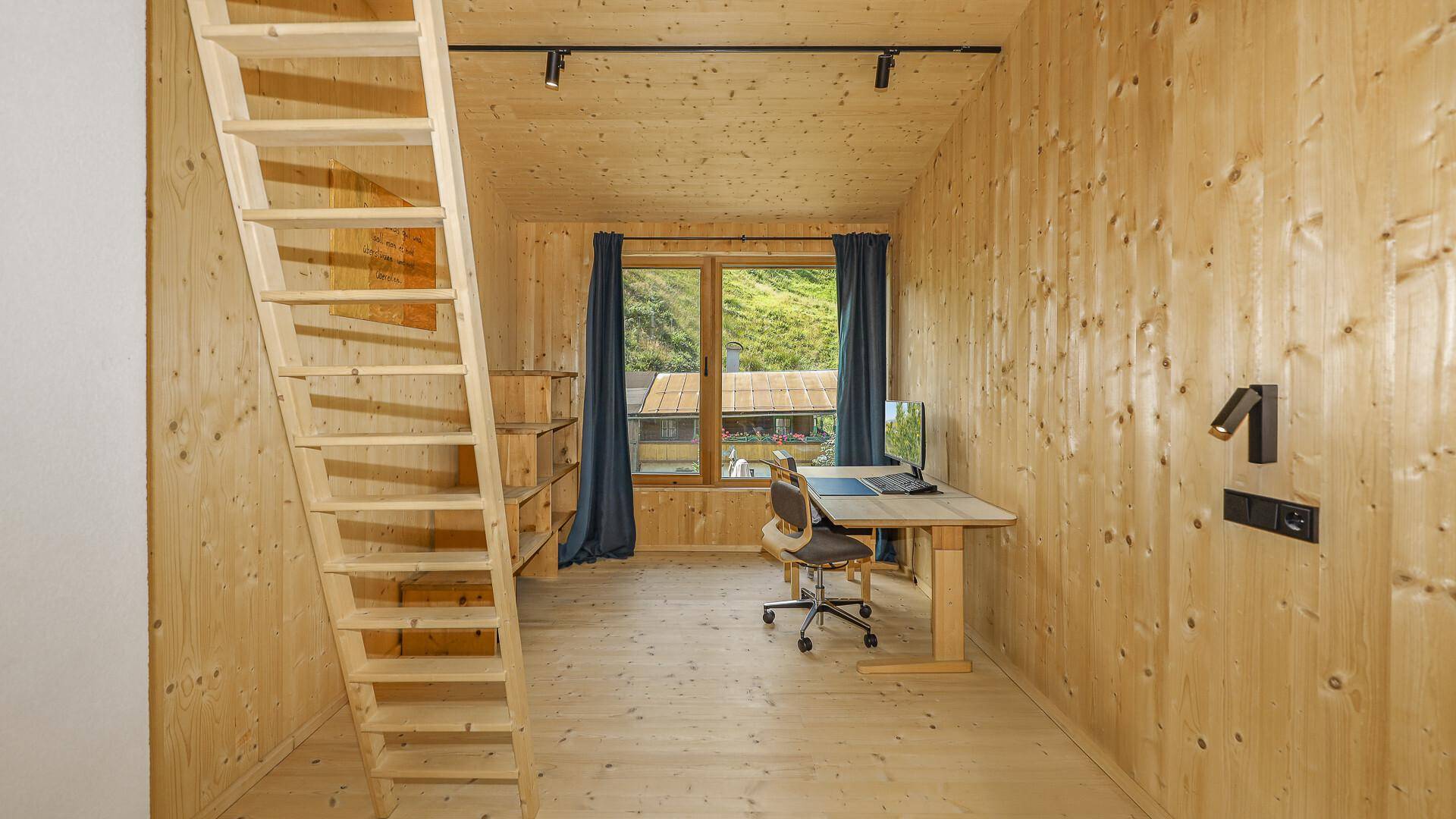 Arbeitszimmer mit Holzwänden, Schreibtisch und Hochbett, ideal für konzentriertes Arbeiten.