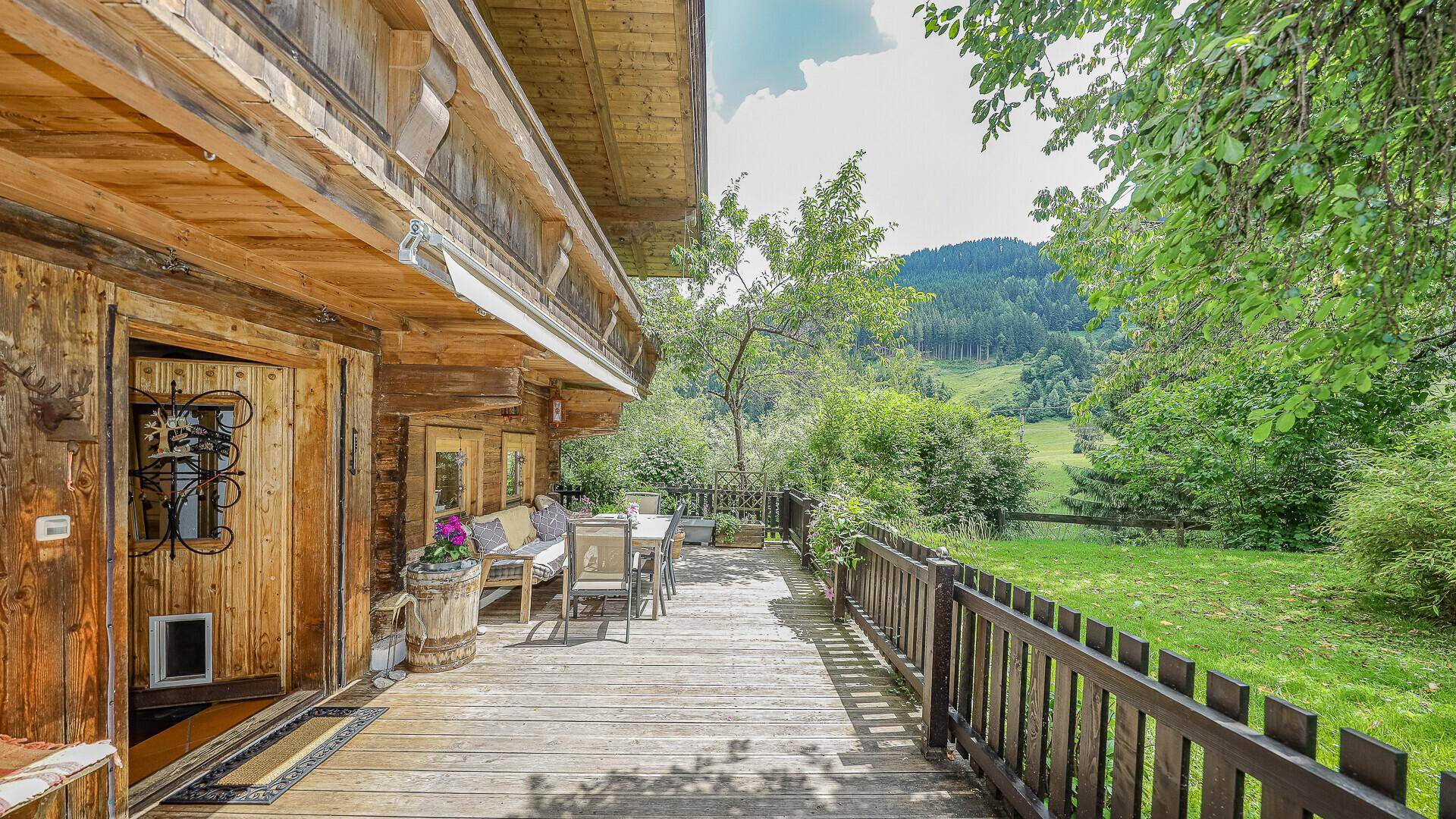 Geräumige Holzterrasse mit Gartenmöbeln und Blick auf die grüne Landschaft.
