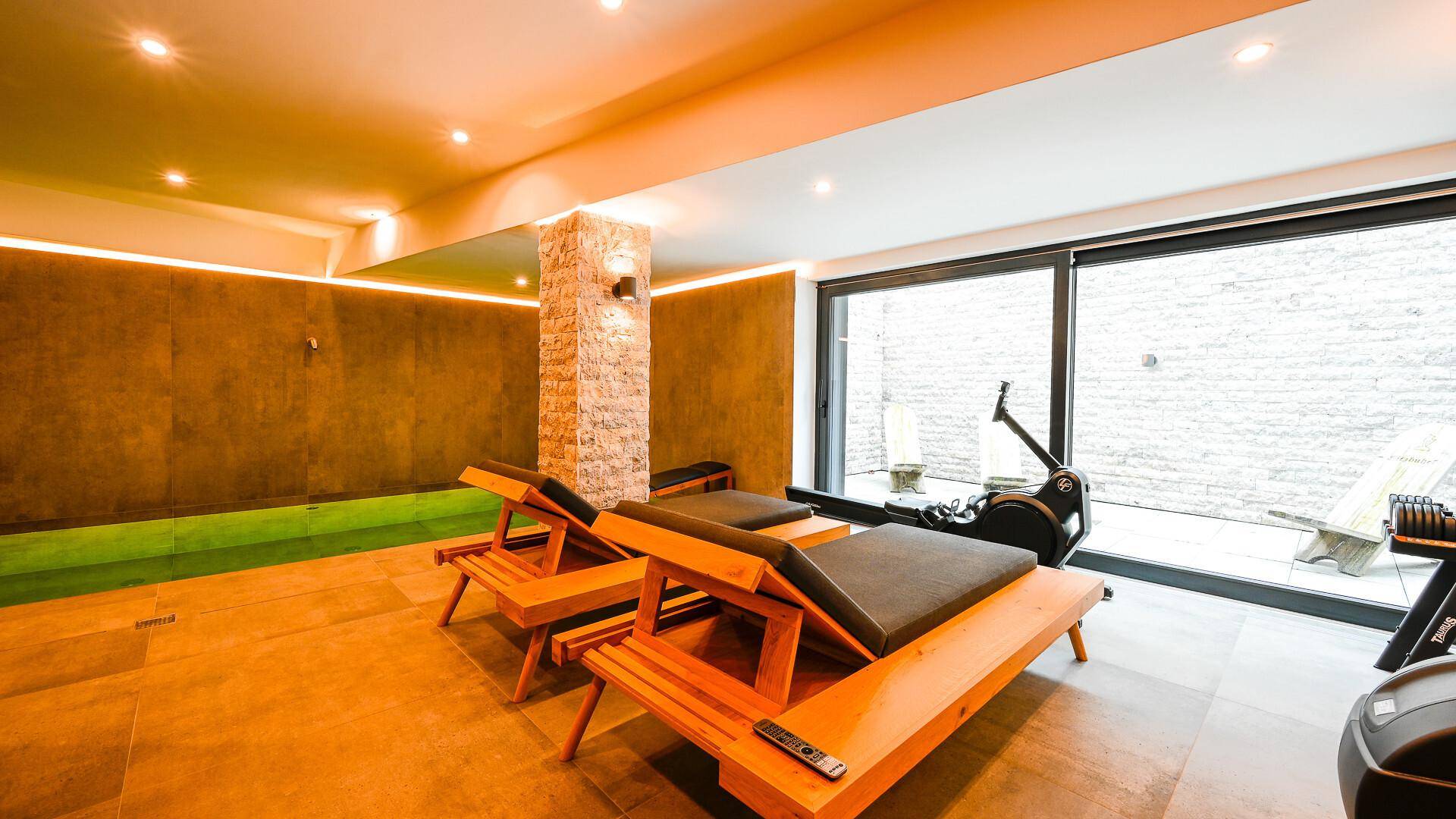 Entspannungsbereich im Wellnessbereich mit Liegestühlen und Blick auf den Außenbereich.