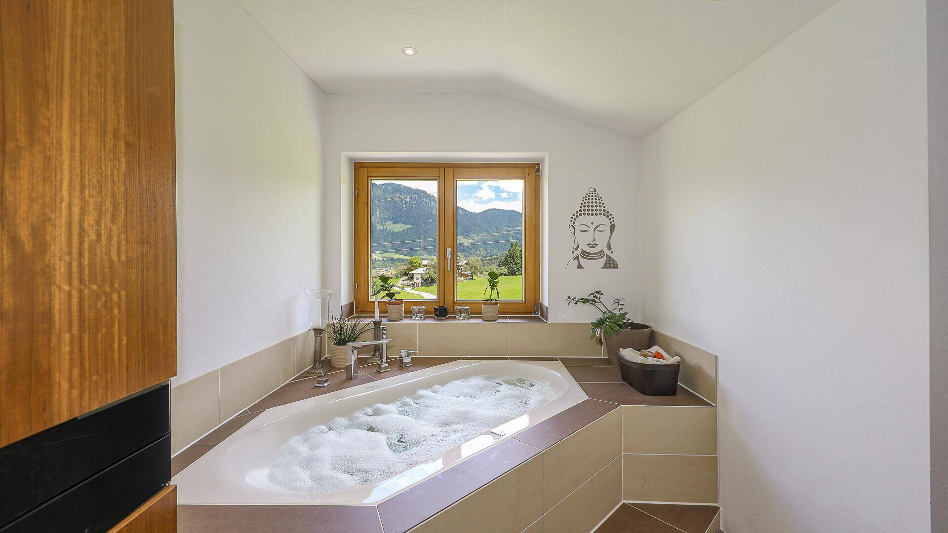 Modernes Badezimmer mit eingebauter Badewanne und Fensterblick auf die Berge.