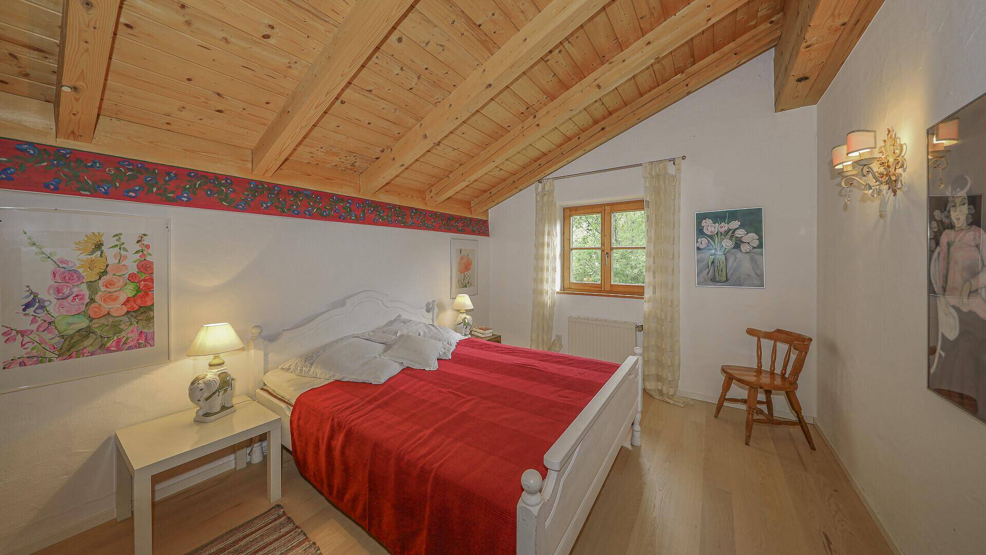Schlafzimmer im Dachgeschoss mit Holzbalkendecke, Holzboden und traditioneller Dekoration.
