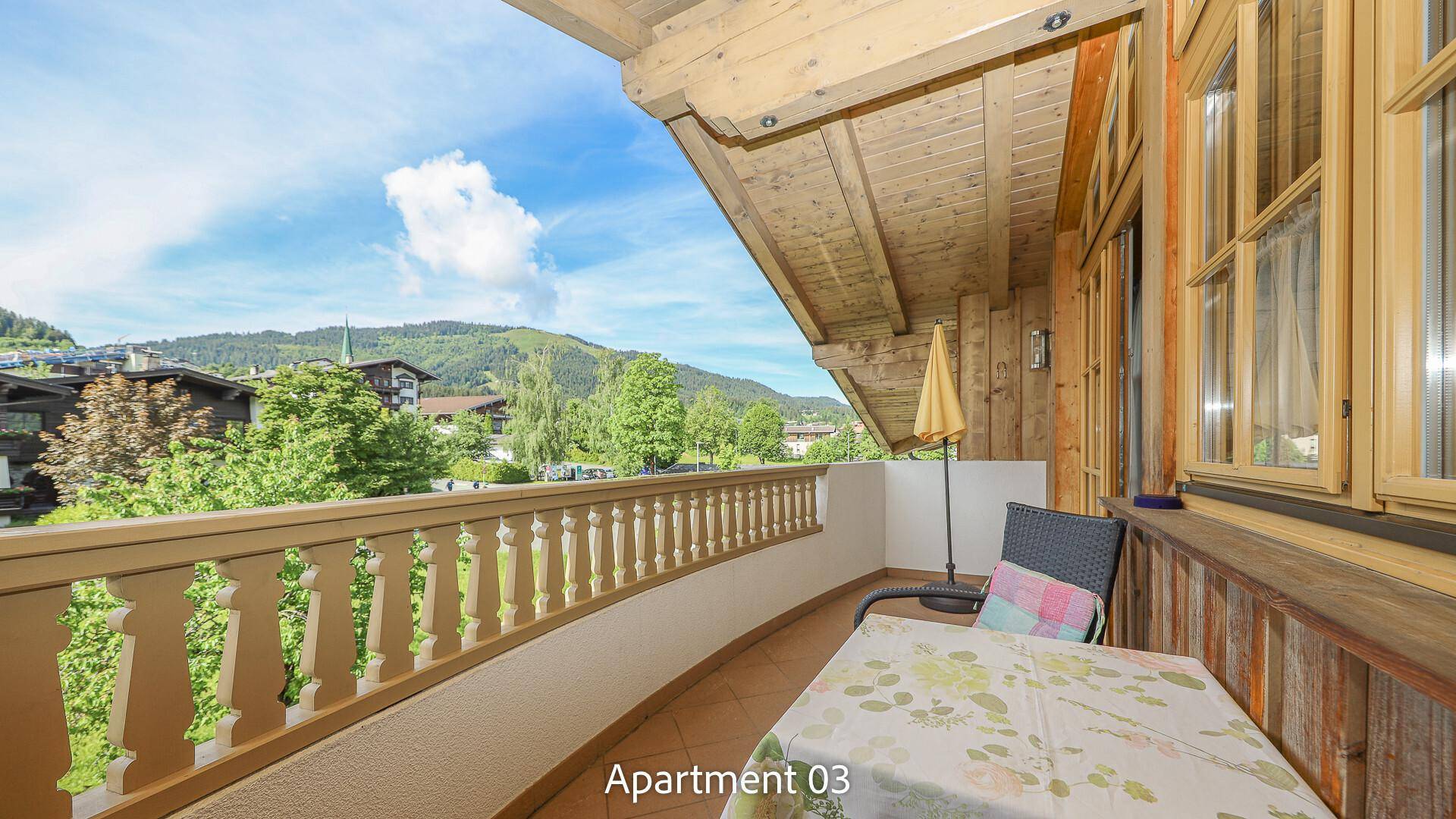 Sonniger Balkon mit Sitzgelegenheiten und Blick auf die grüne Umgebung.