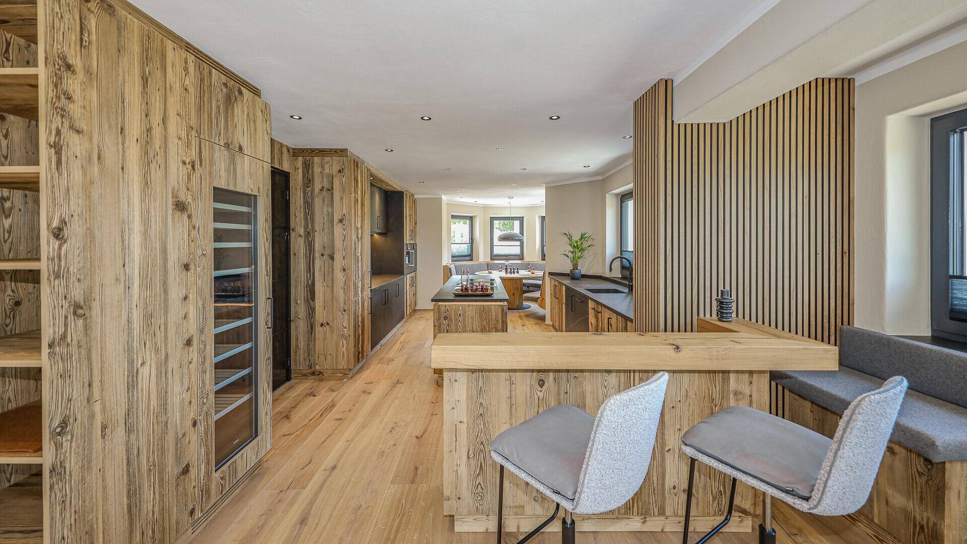 Moderne Holzküche mit integrierten Geräten, Frühstücksbar und offenem Design.