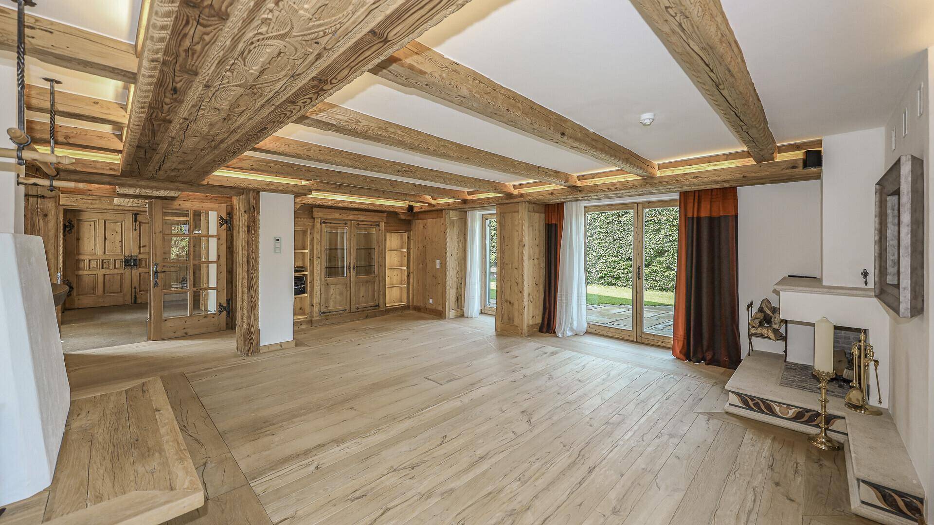 Gemütliches Wohnzimmer mit Holzboden, Kamin und traditionellen Holzelementen.