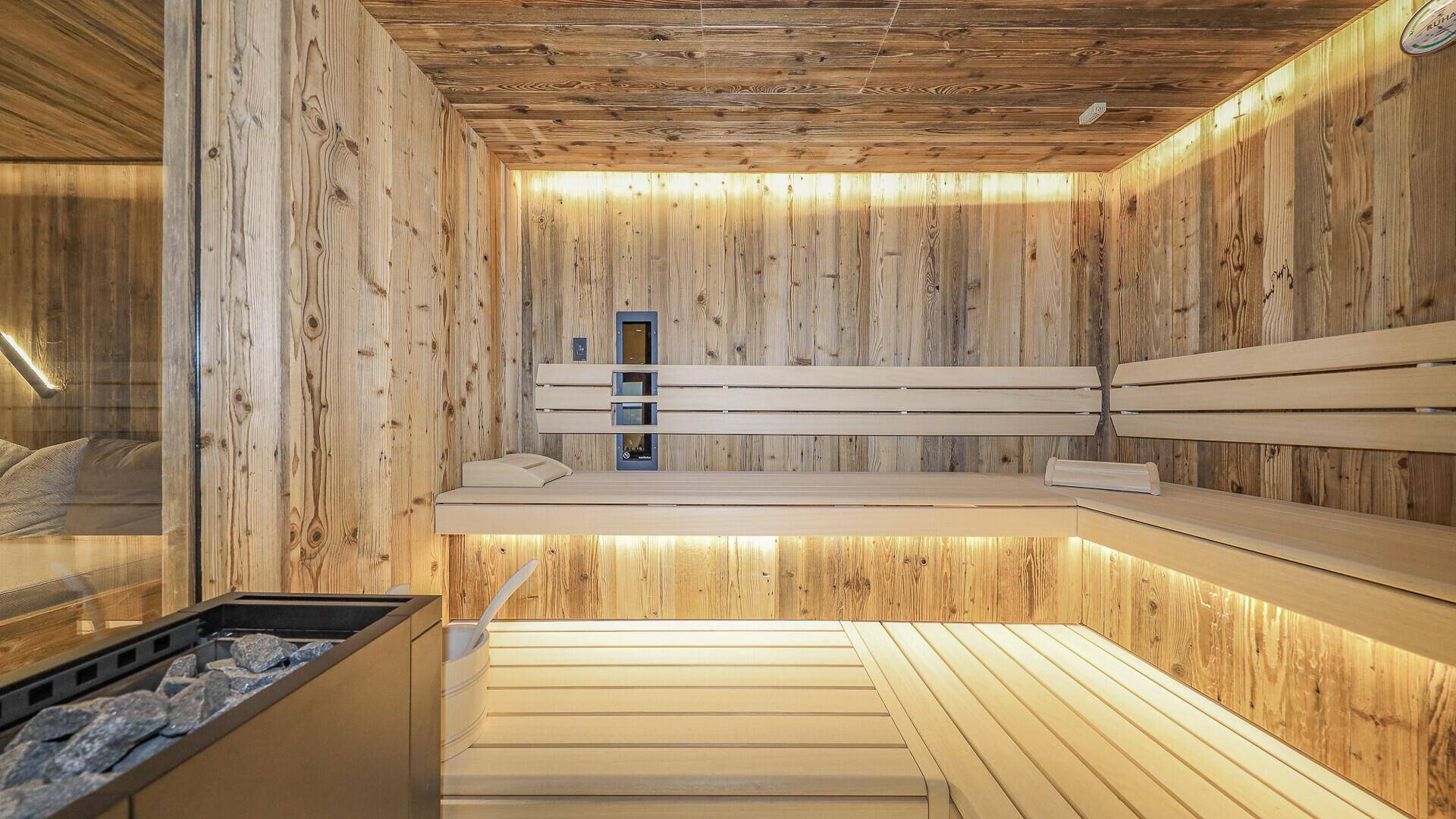Innenansicht der Sauna mit Holzbänken und stimmungsvoller Beleuchtung für maximale Entspannung.