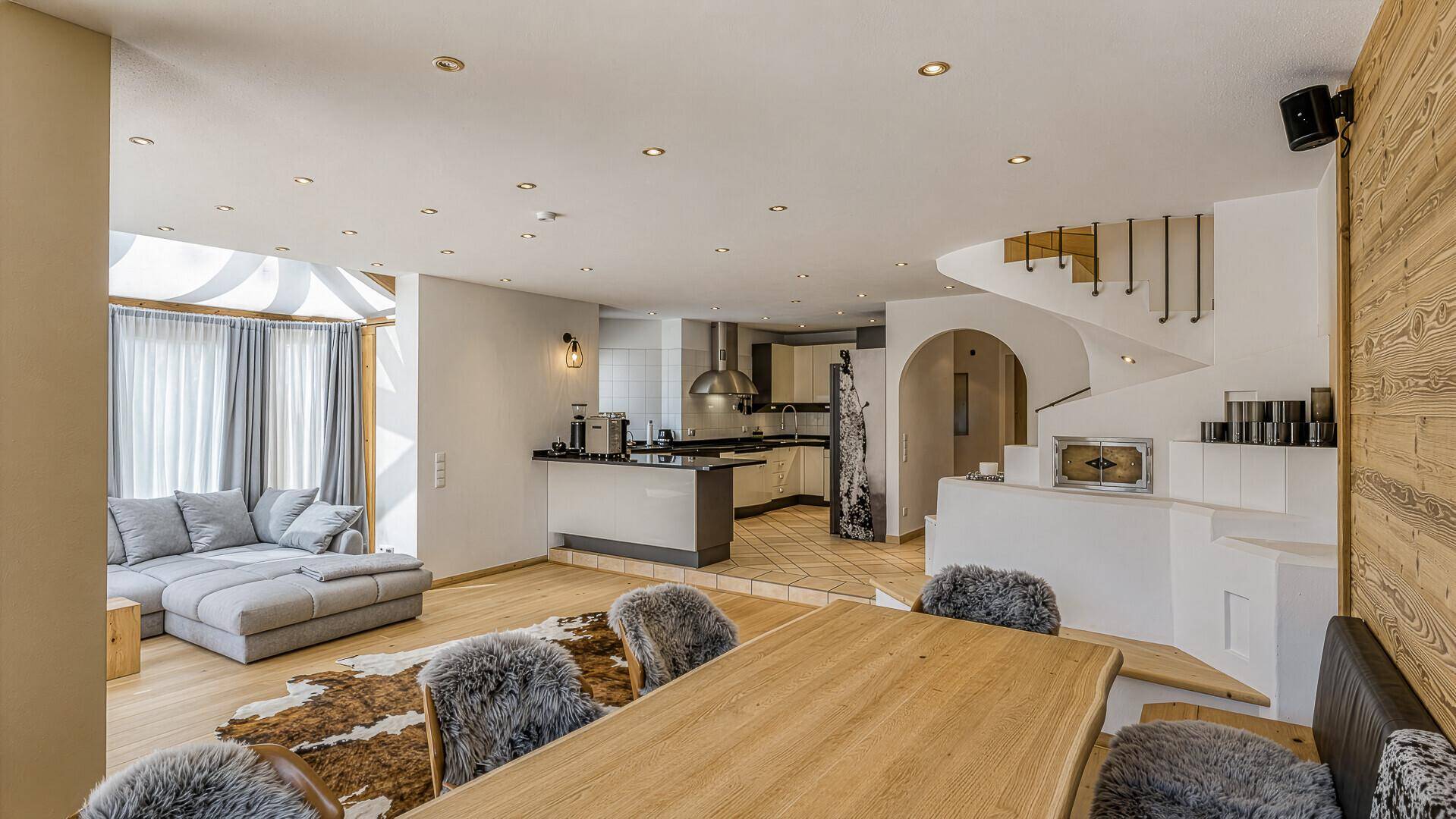 Offener Wohn-Essbereich mit Holzboden, moderner Einrichtung und Blick auf die Küche und Treppe.