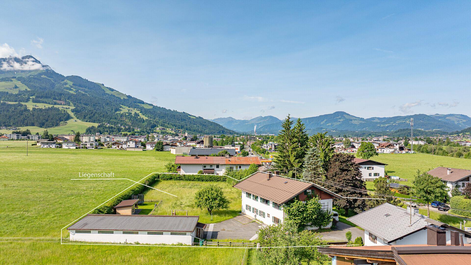 Panoramablick auf das Anwesen mit weiten Grünflächen und der beeindruckenden Berglandschaft.