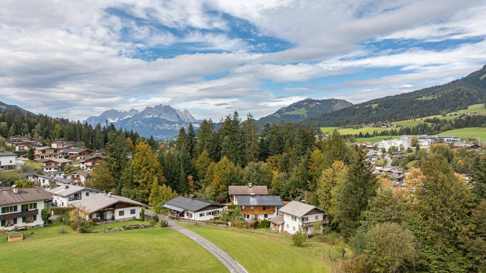 Weitläufige Ansicht einer idyllischen Wohngegend, umgeben von Wäldern und mit Blick auf die Alpen.