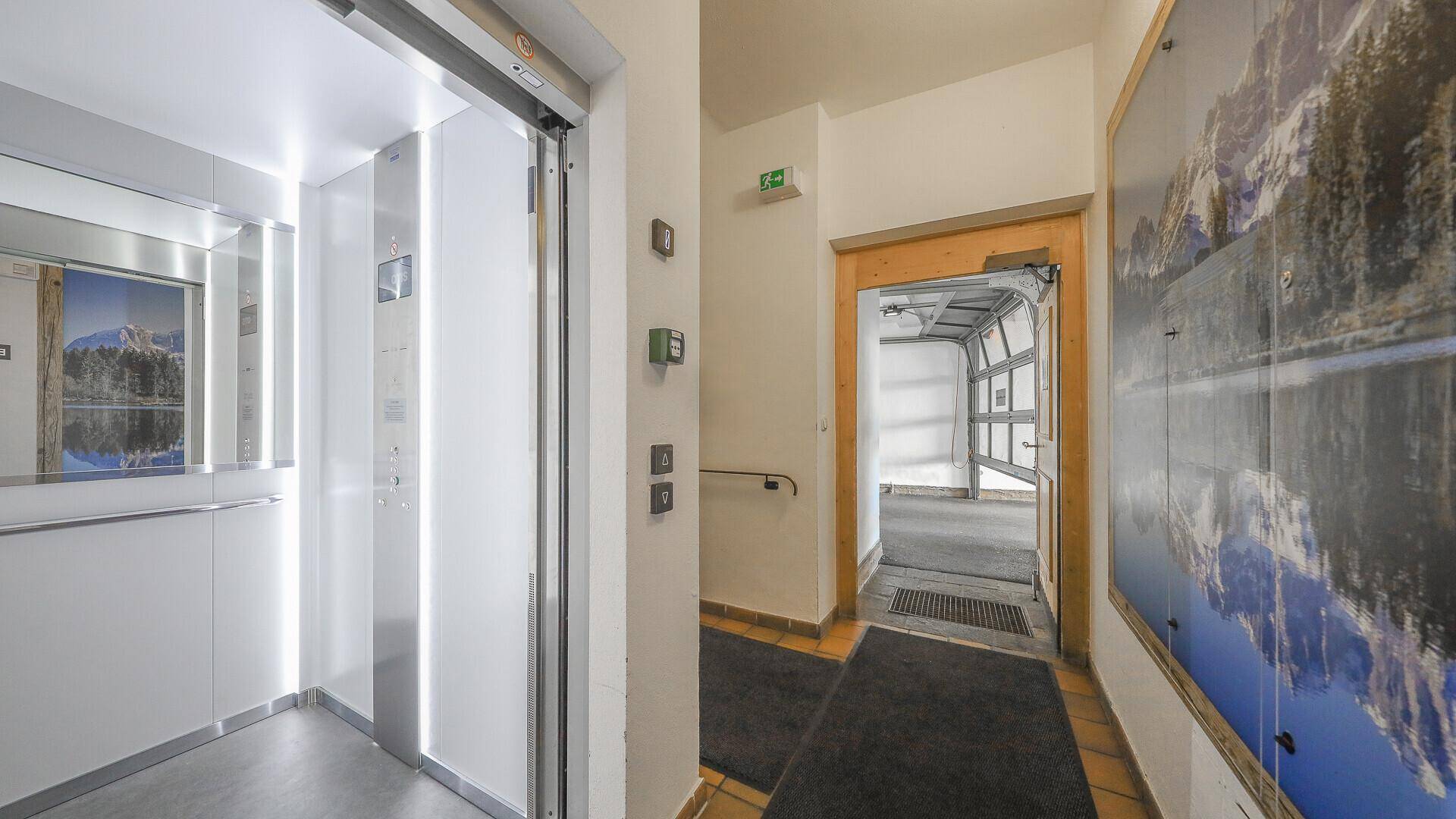 Heller Eingangsbereich mit modernem Aufzug und Zugang zur Garage.