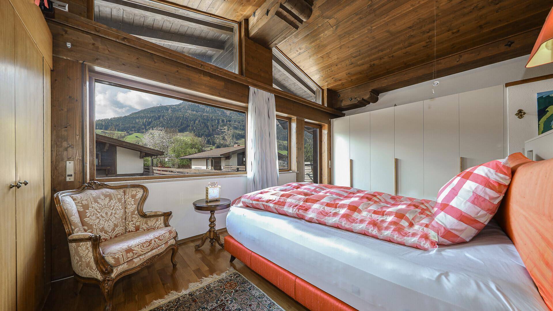 Gemütliches Schlafzimmer mit Holzbalkendecke, Einbauschränken und Bergblick.
