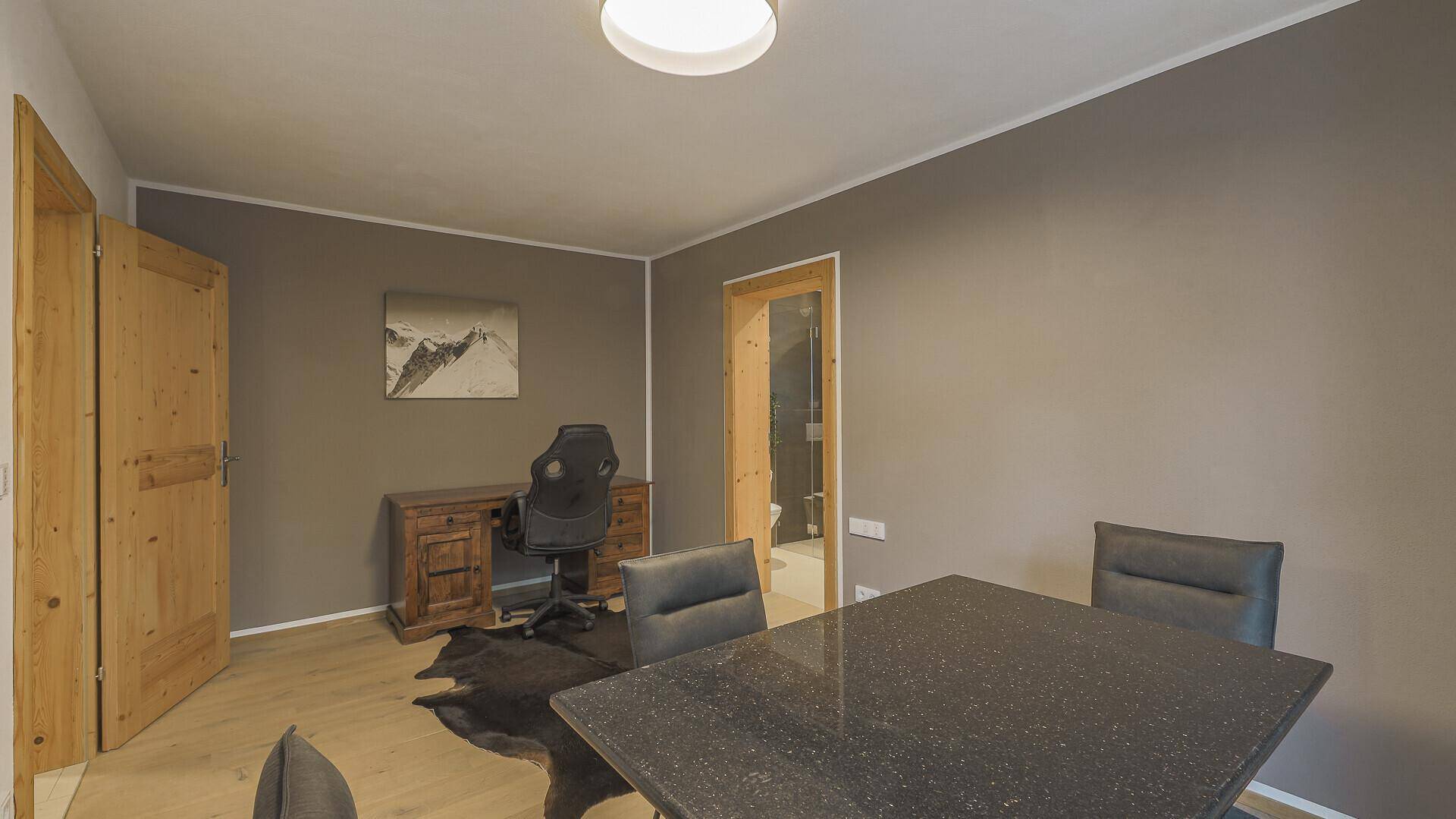 Funktionaler Arbeitsraum mit Schreibtisch, Stuhl und zusätzlichem Tisch für Besprechungen.