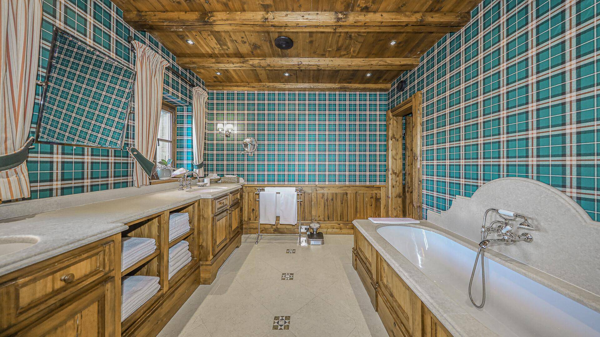 Geräumiges Badezimmer mit karierter Tapete, Holzelementen und großer Badewanne.