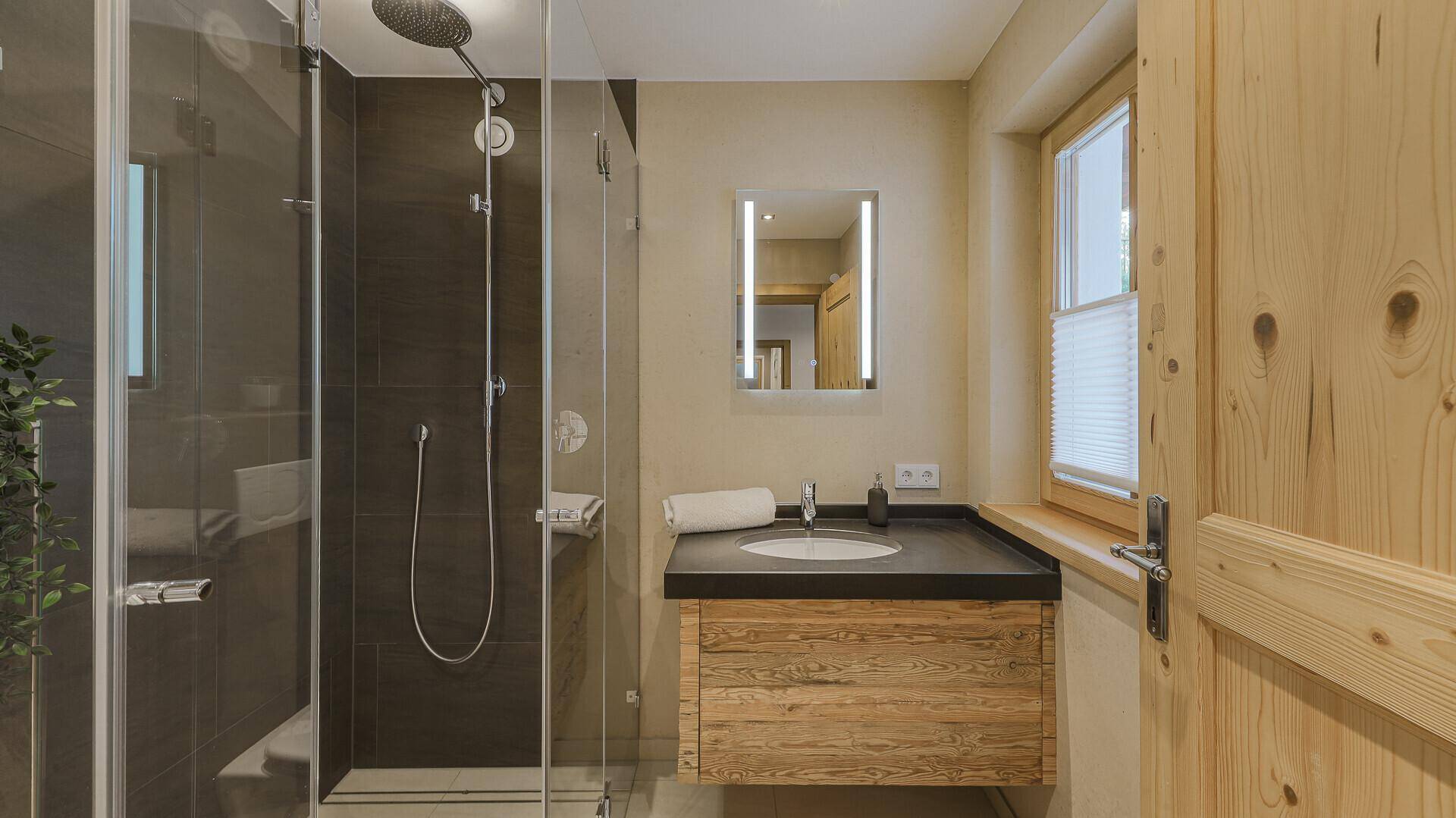 Modernes Badezimmer mit Einzelwaschbecken, begehbarer Dusche und Fenster für Tageslicht.