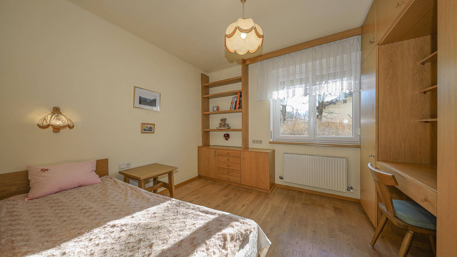 Helles Schlafzimmer im traditionellen Stil mit Einzelbett, Schreibtisch und Holzregalen.
