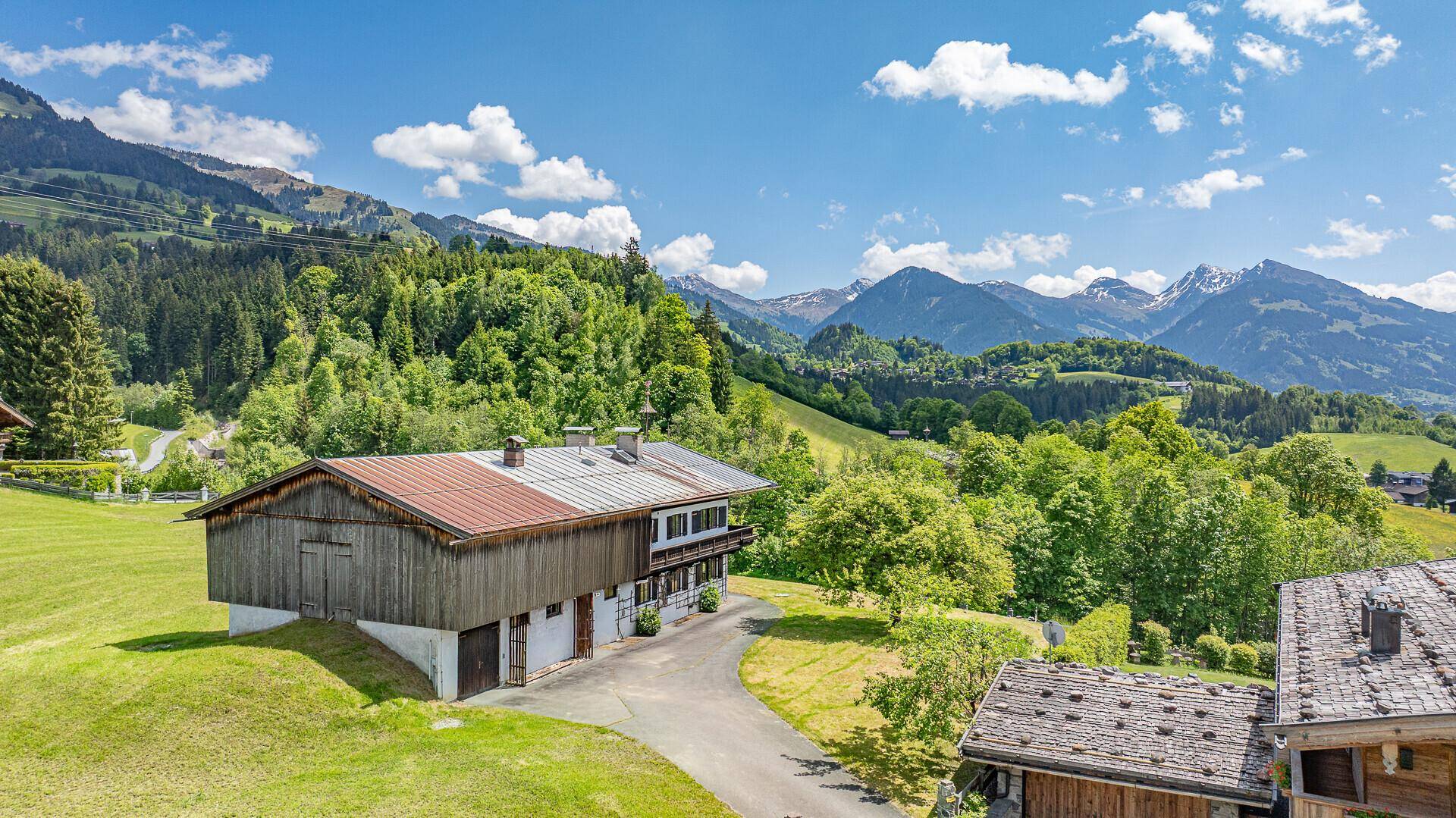 Ländliches Anwesen mit Nebengebäude und weitem Blick auf die alpine Landschaft.