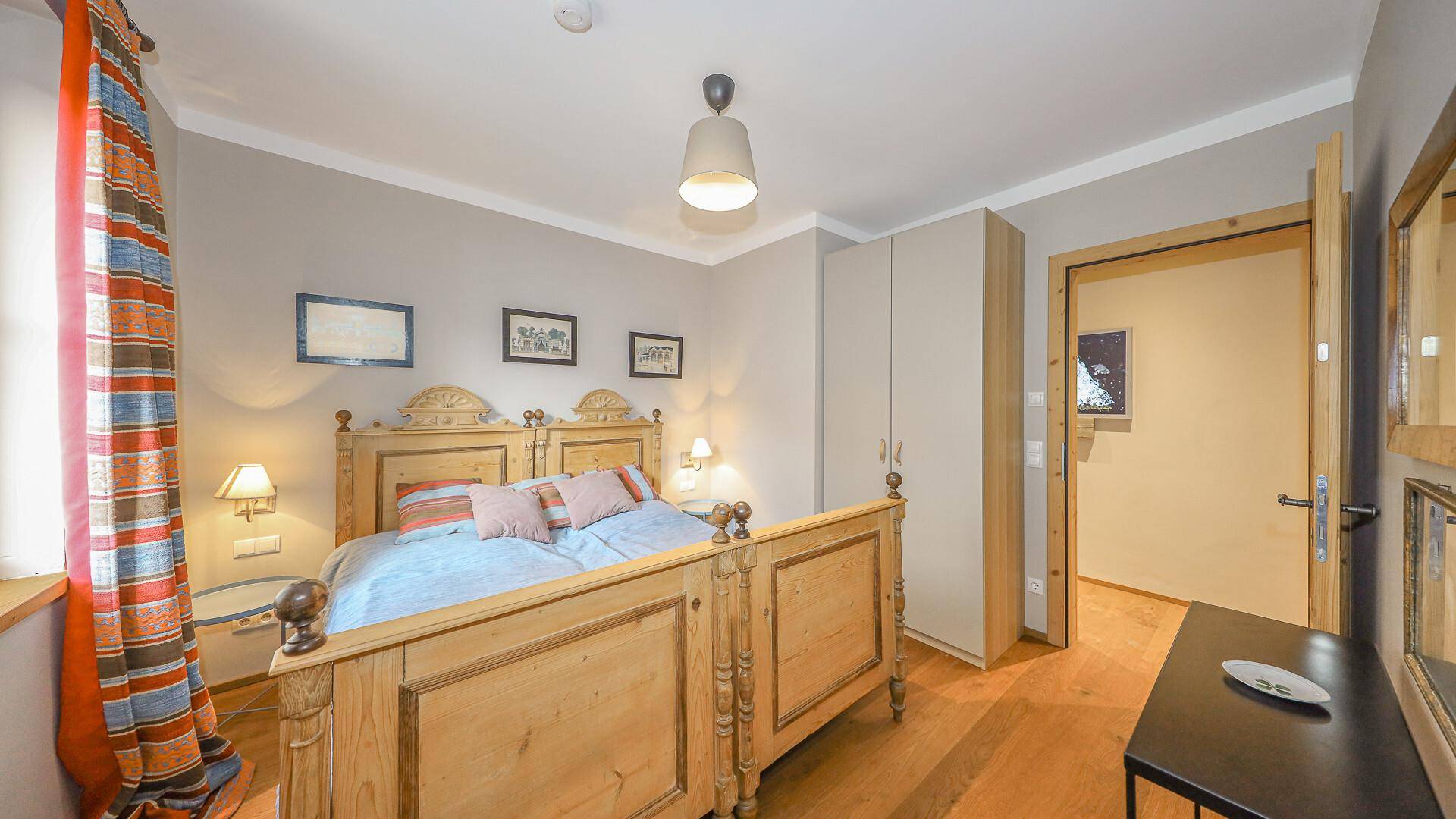 Schlafzimmer mit traditionellem Holzbett, Holzboden und Kleiderschrank.