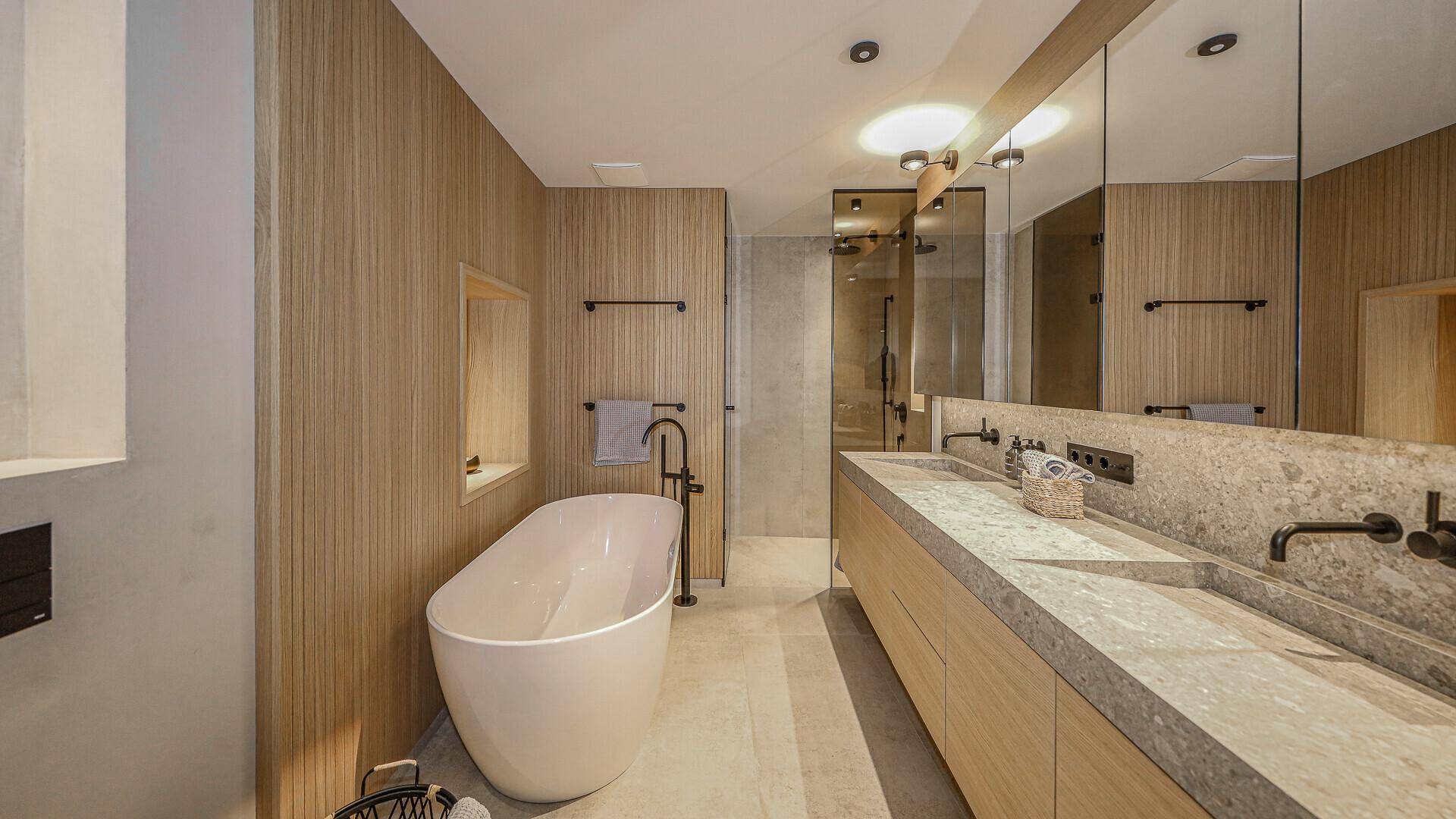 Modernes Badezimmer mit freistehender Badewanne, Doppelwaschbecken und Holzverkleidung.