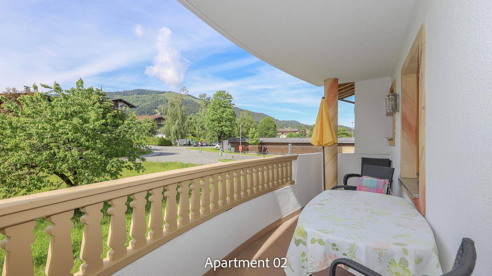 Sonniger Balkon mit Sitzgelegenheiten und Blick auf die grüne Umgebung.