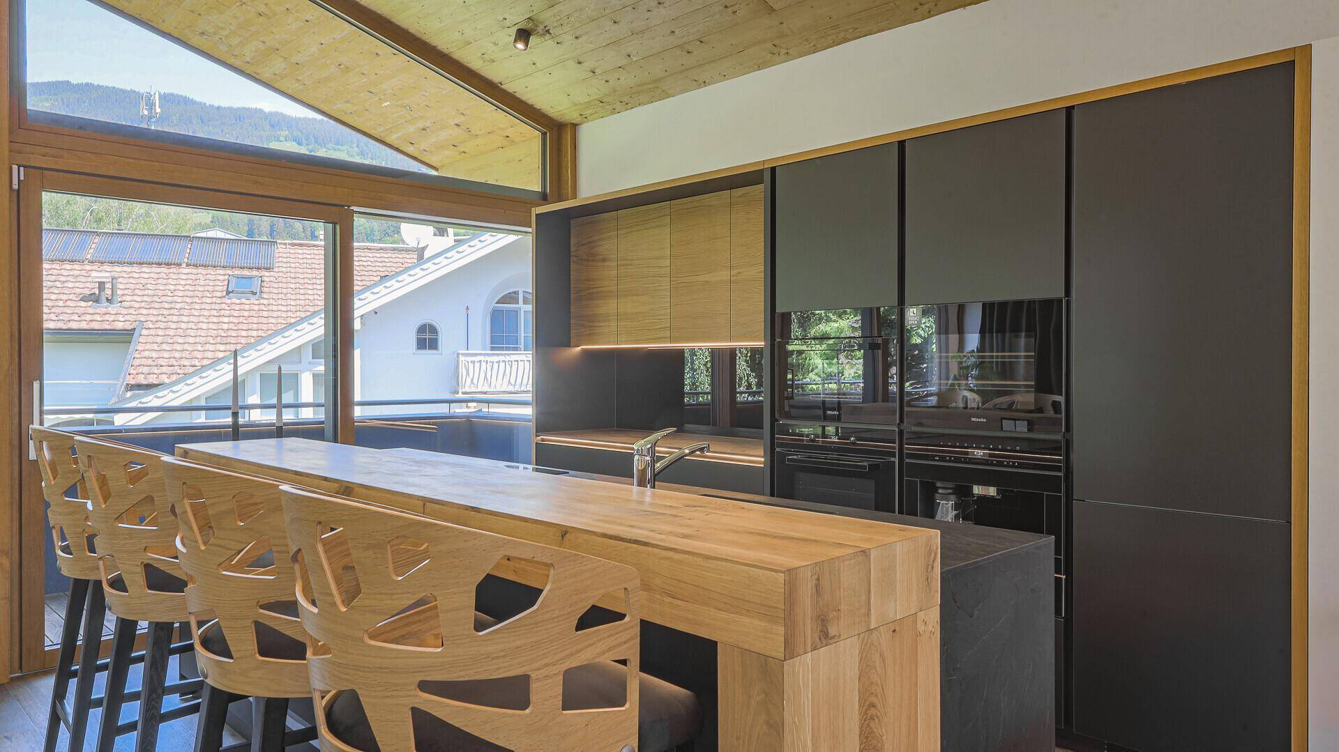 Elegante Küche mit dunklen Fronten, Holzdetails und integrierten Geräten, sehr modern.