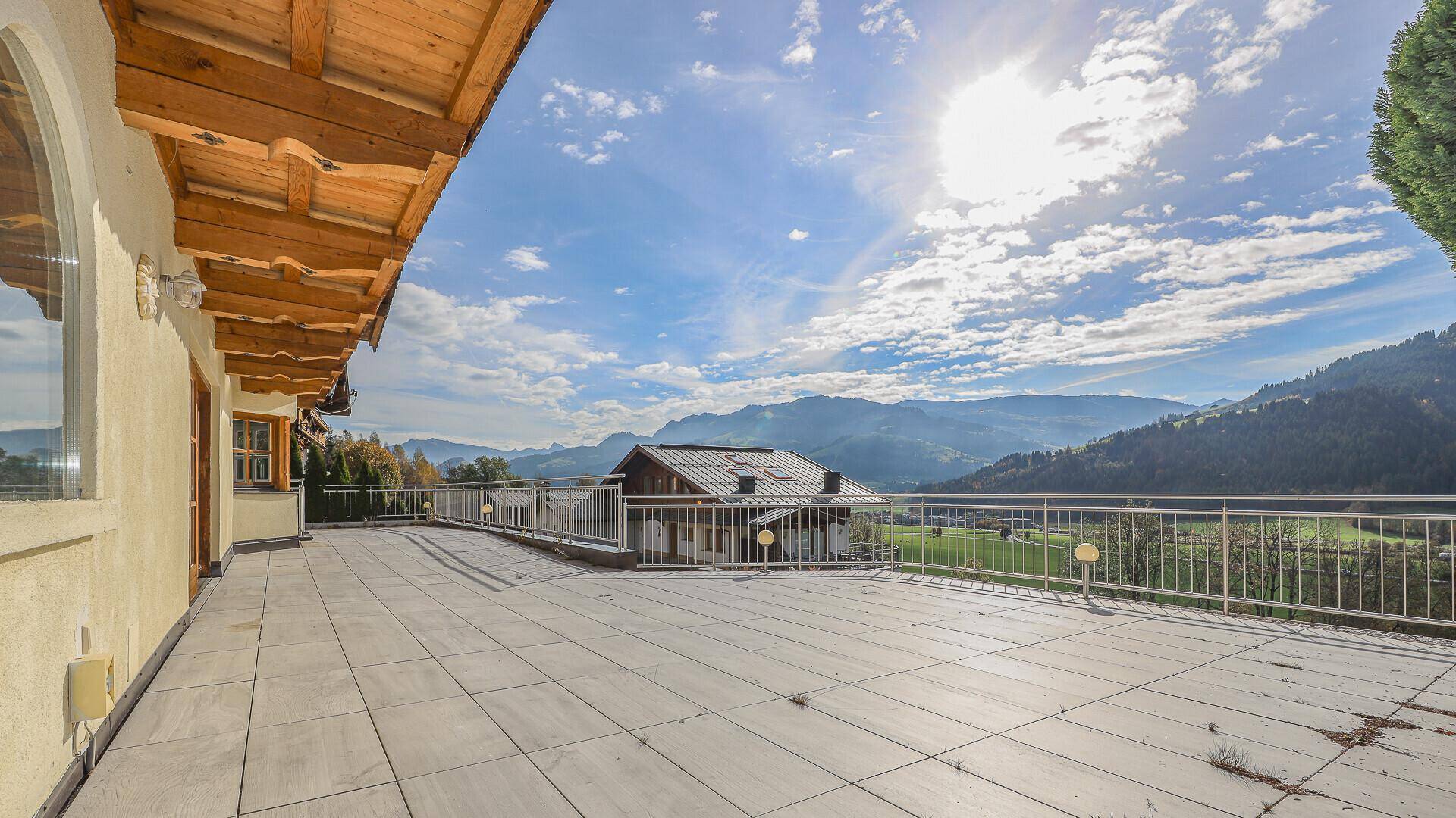 Großzügige geflieste Terrasse mit weitem Panoramablick auf die umliegenden Berge und das Tal.