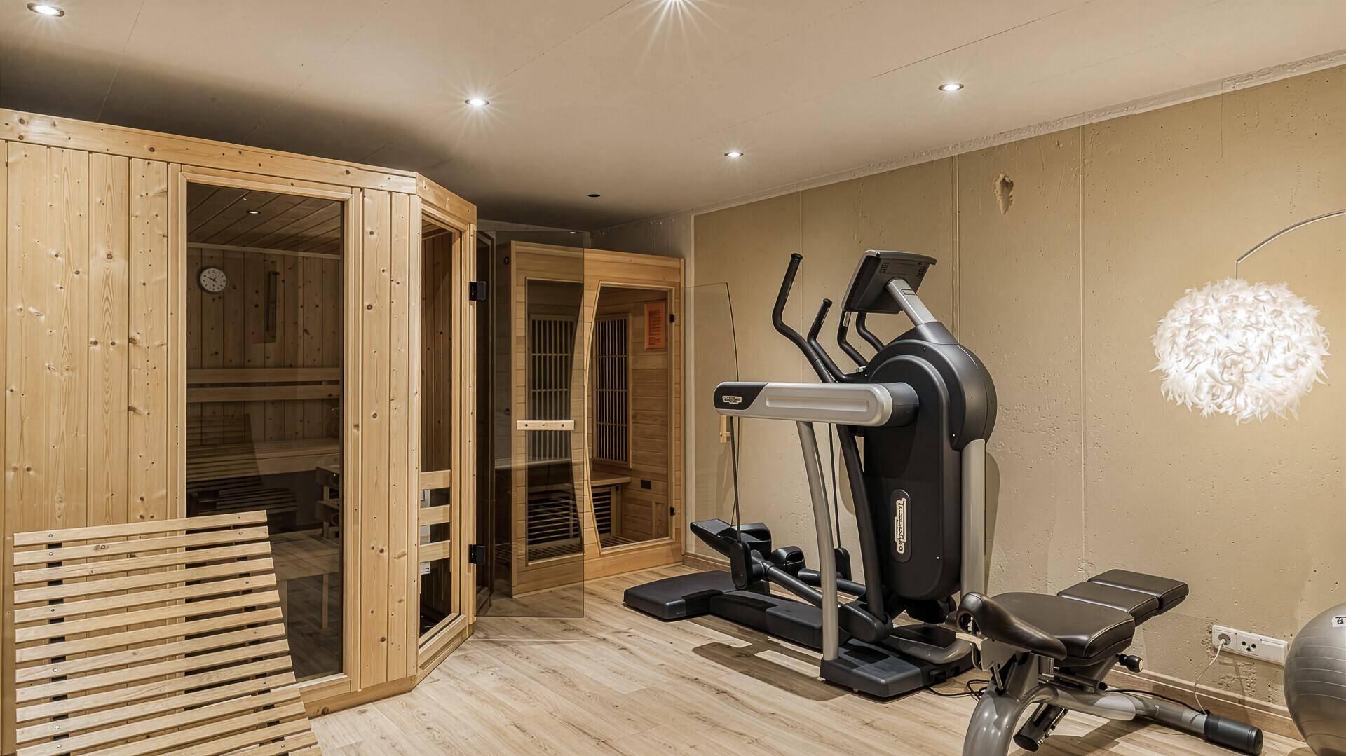 Moderner Wellnessbereich mit Sauna und Fitnessgeräten für Entspannung und Training.