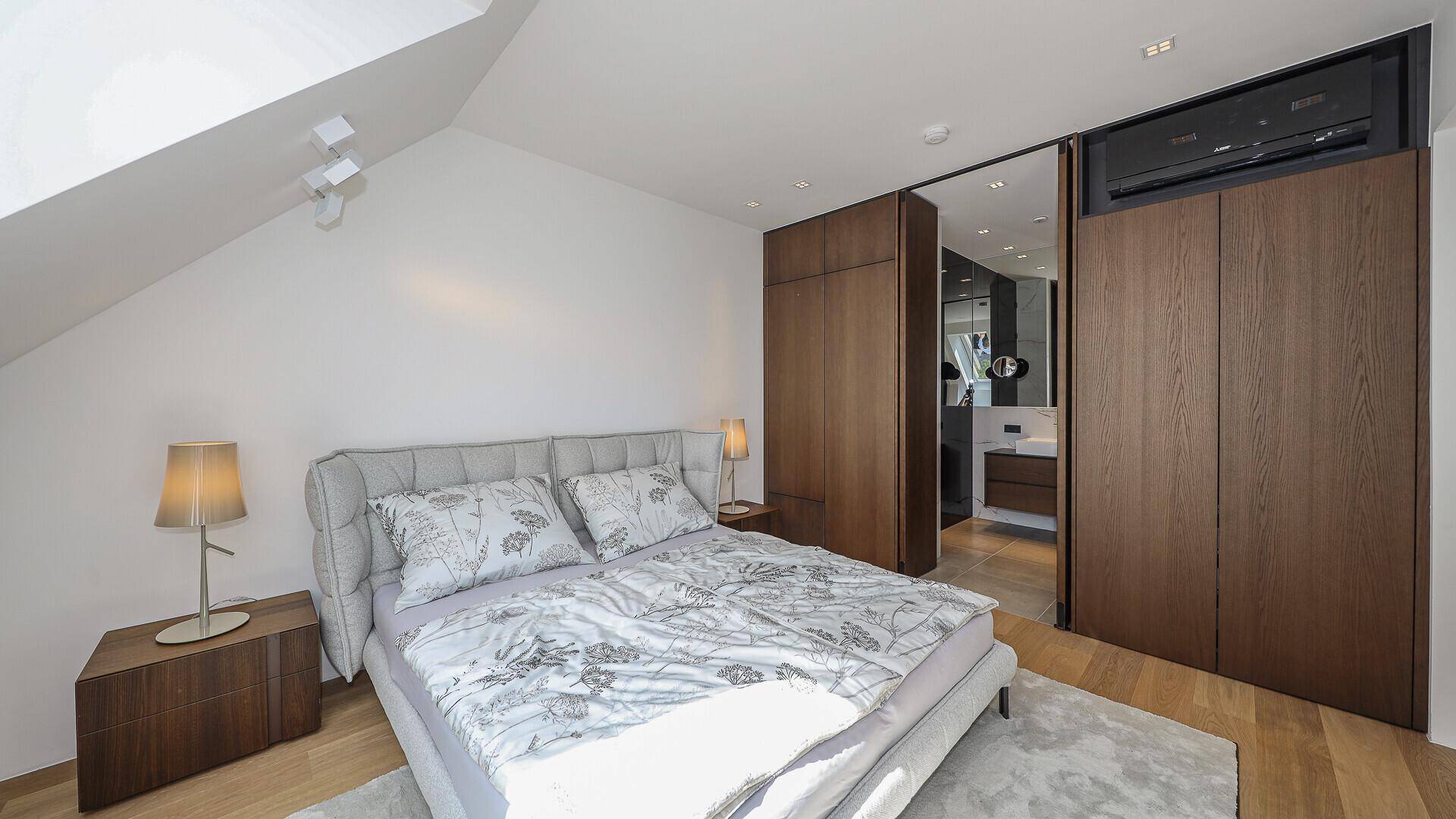 Schlafzimmer mit Holzboden und integrierten Schränken, die zum angrenzenden Badezimmer führen.