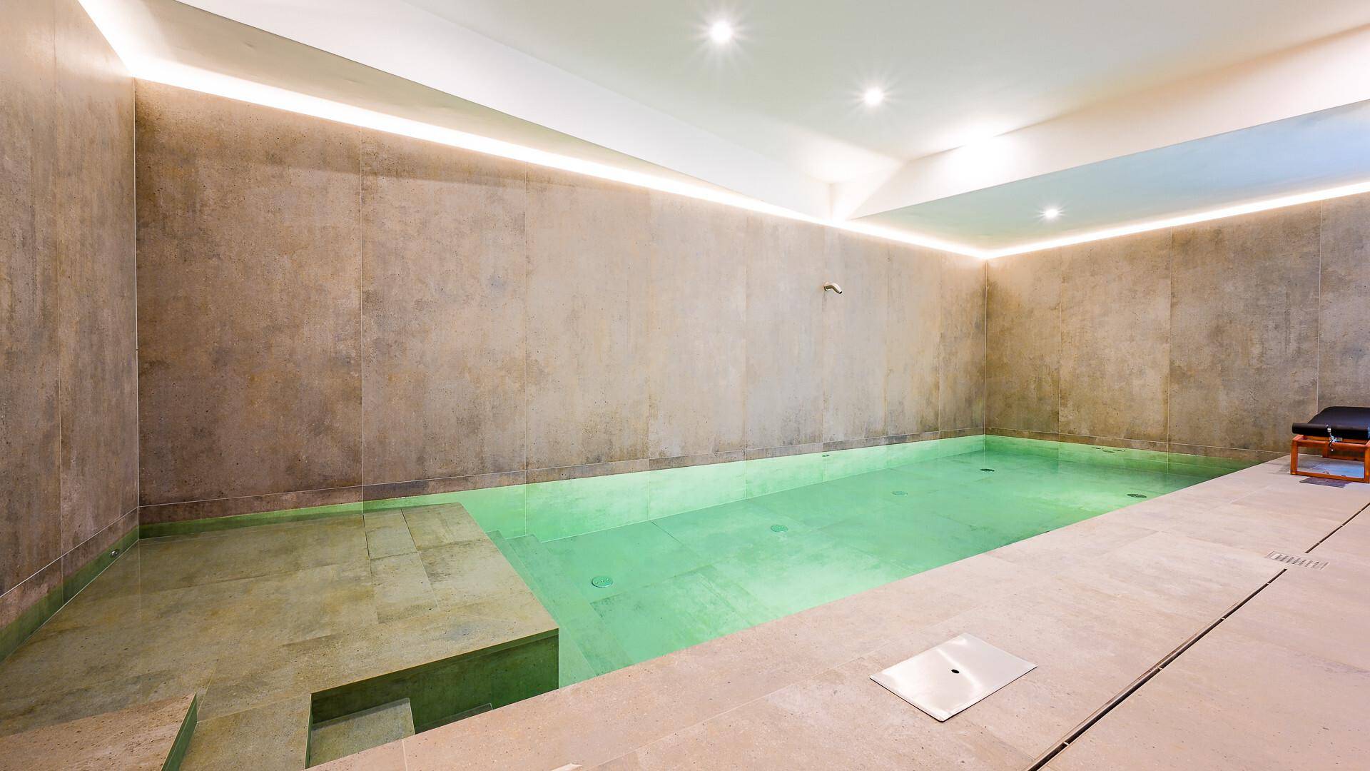 Innenpoolbereich mit modernem Design, Steinwänden und indirekter Beleuchtung.