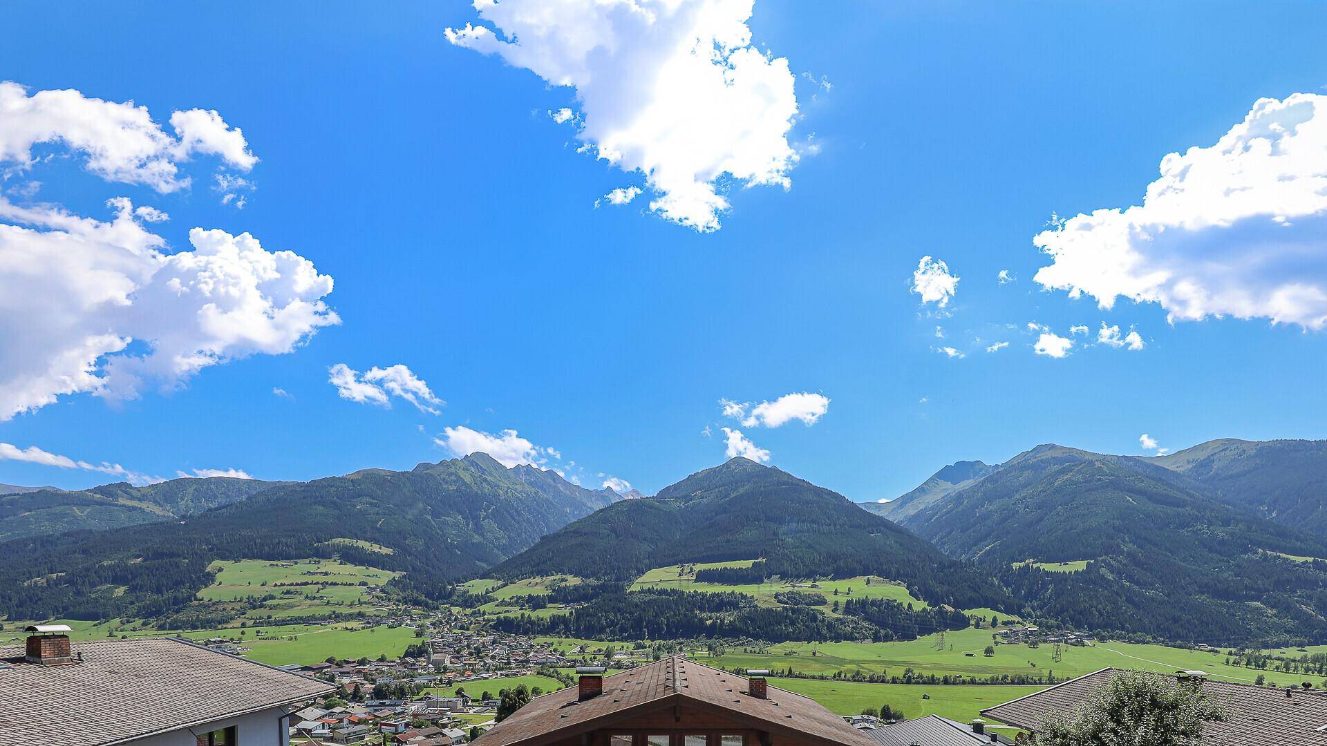 Atemberaubender Panoramablick auf die weite grüne Berglandschaft unter blauem Himmel.