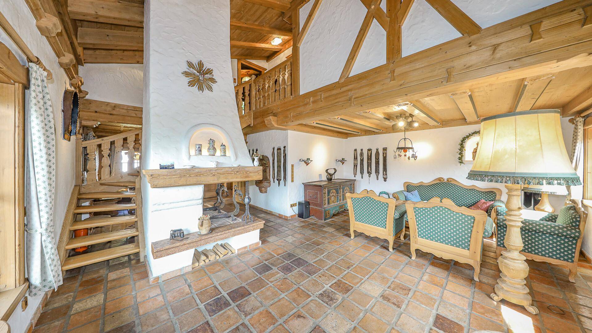 Traditionelles Wohnzimmer im alpinen Stil mit Kamin, Holzbalken und rustikalen Möbeln.