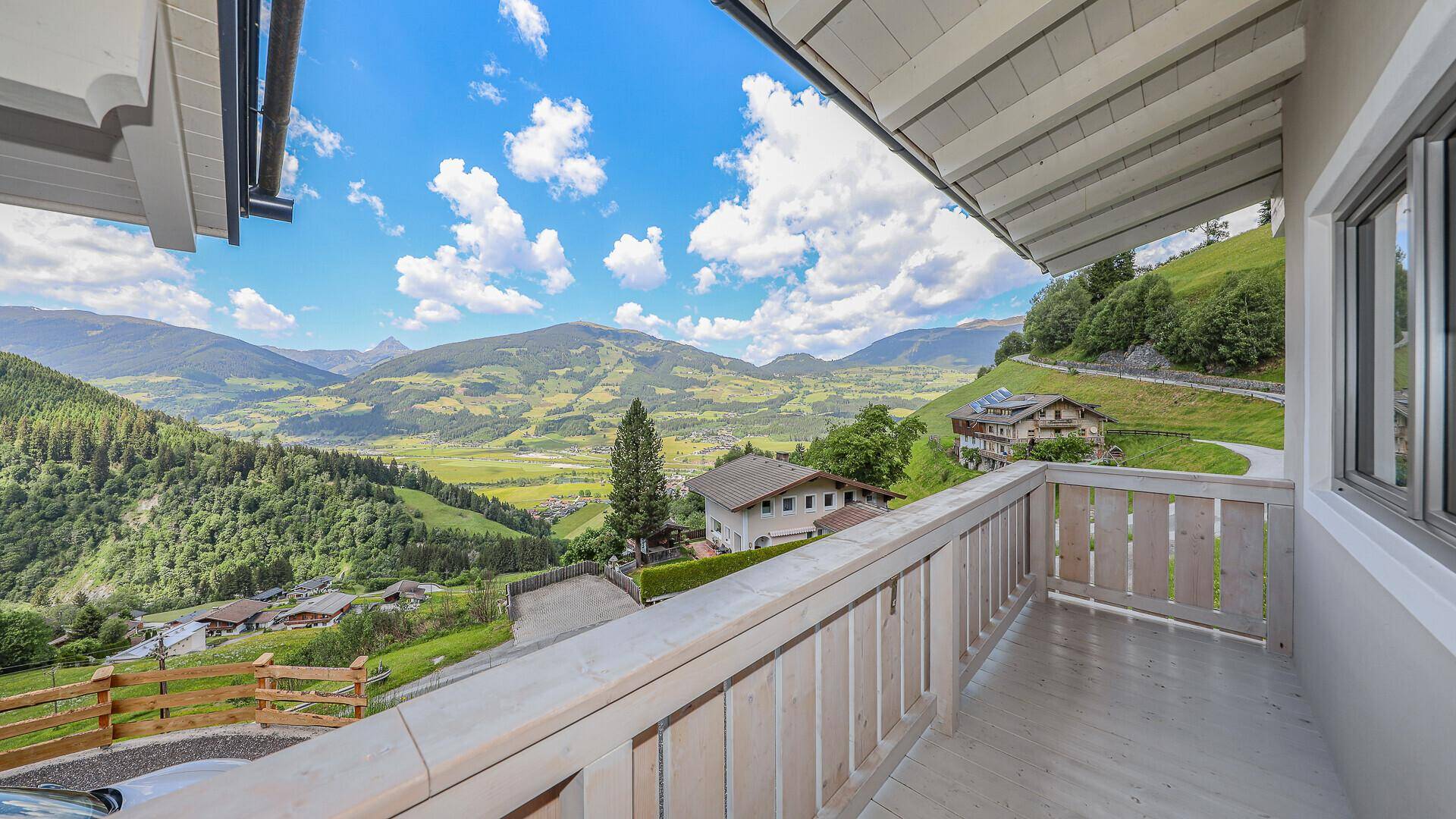 Langer Balkon mit traditionellem Holzgeländer und atemberaubendem Panoramablick auf die Alpen.