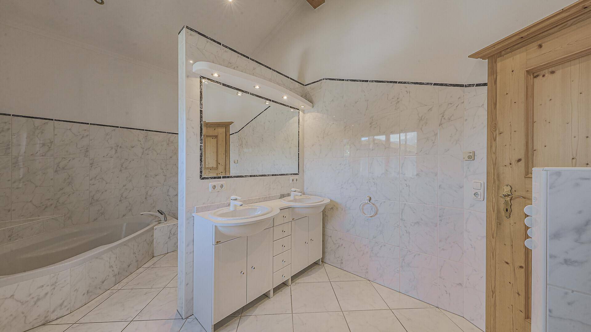 Traditionelles Badezimmer mit Doppelwaschbecken, großer Spiegelfläche und Badewanne.