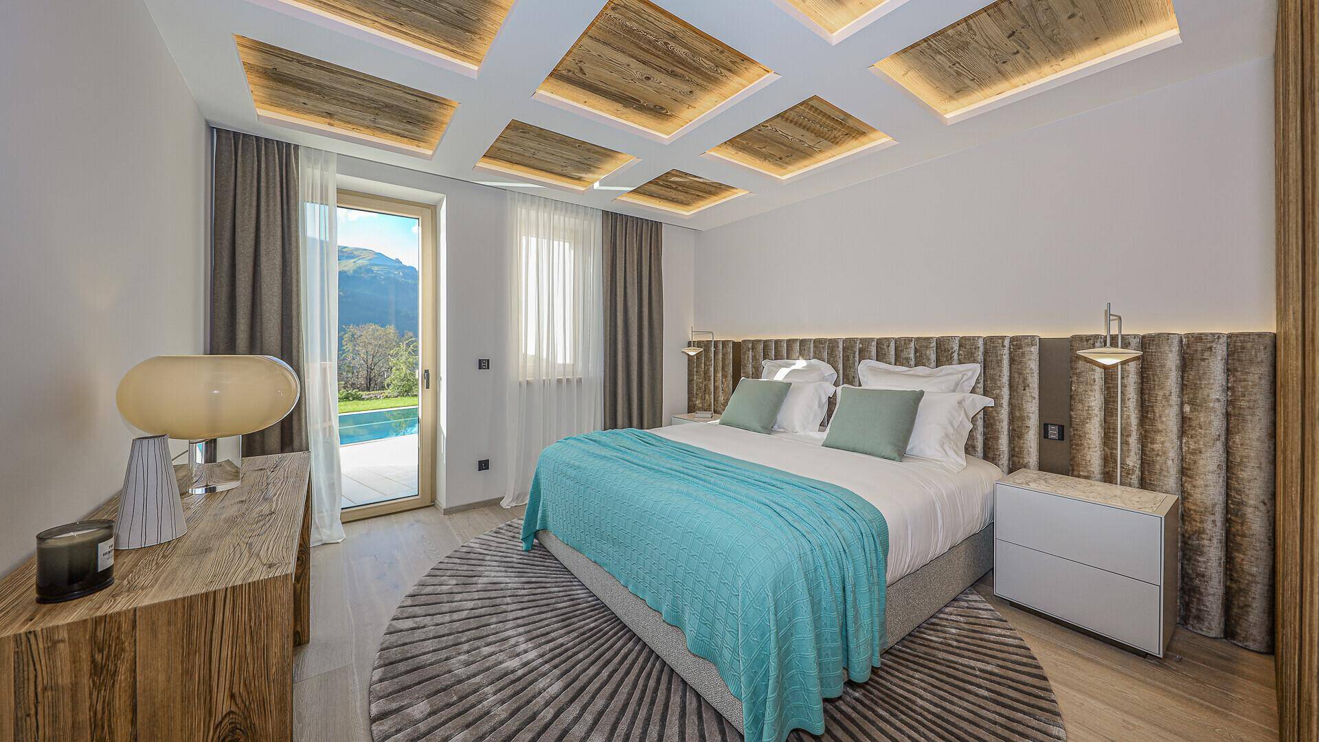 Helles Schlafzimmer mit Zugang zum Poolbereich und Blick auf die umliegende Landschaft.