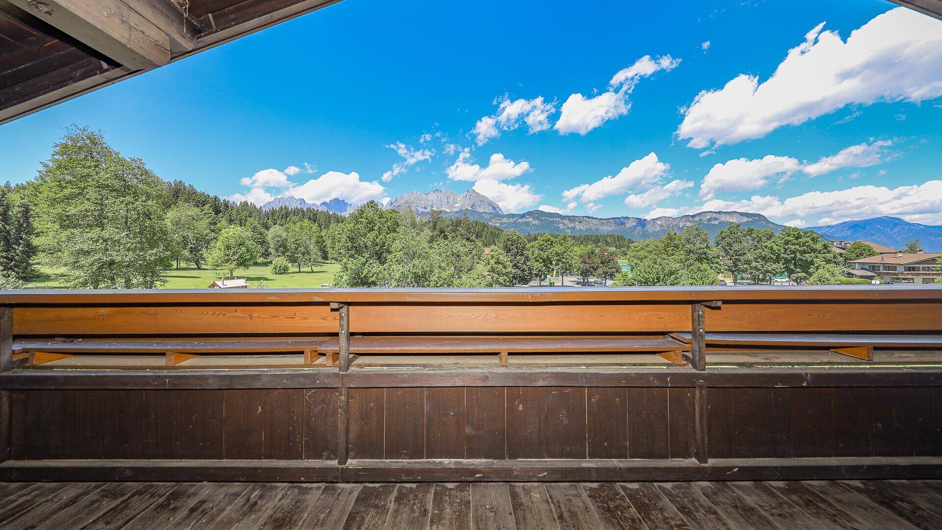 Breiter Holzbalkon mit schöner Aussicht auf die umliegende Berglandschaft und grüne Natur.