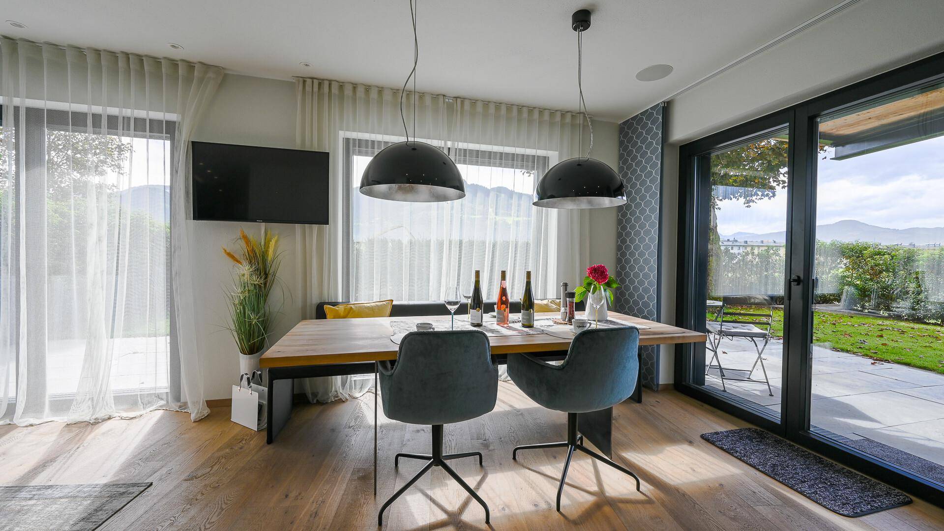 Heller Essbereich mit Holztisch, modernen Stühlen und weitem Blick auf die umliegende Landschaft.