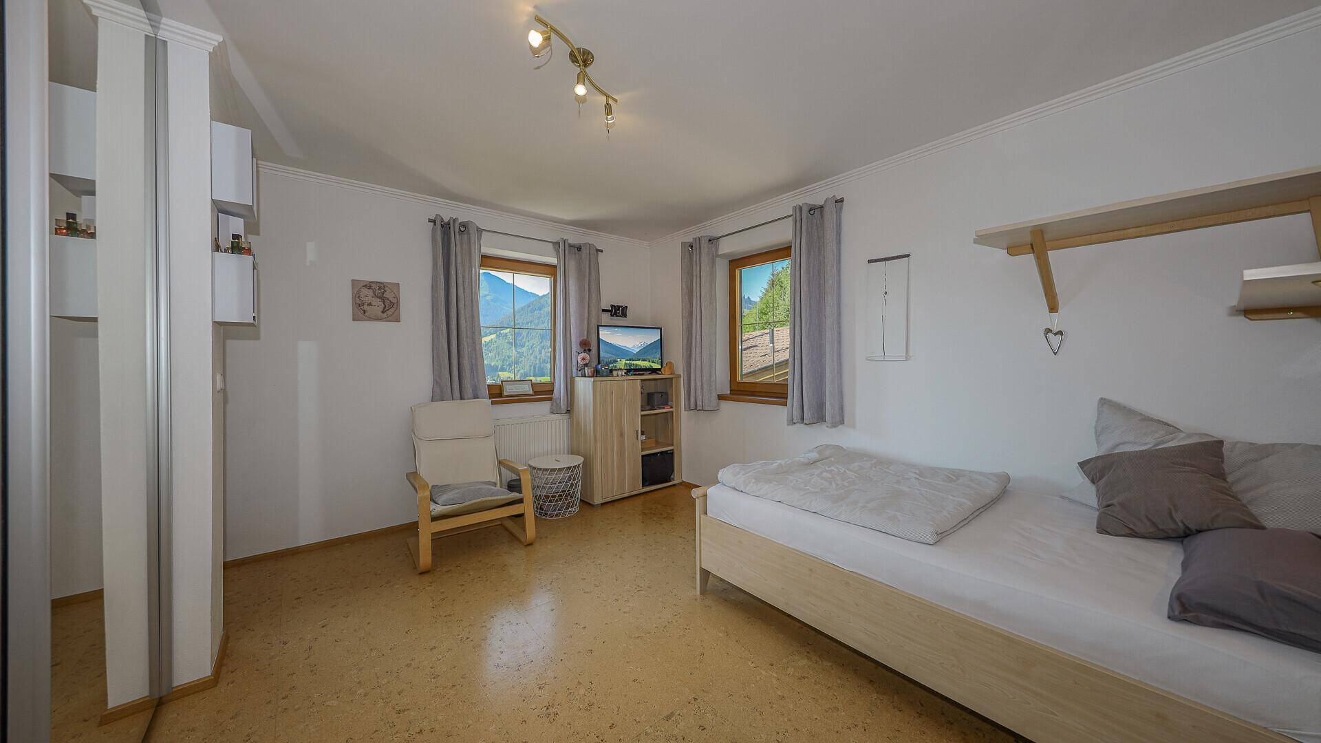 Helles Schlafzimmer mit Einzelbett, Holzdecke und Blick auf die umliegende Natur.