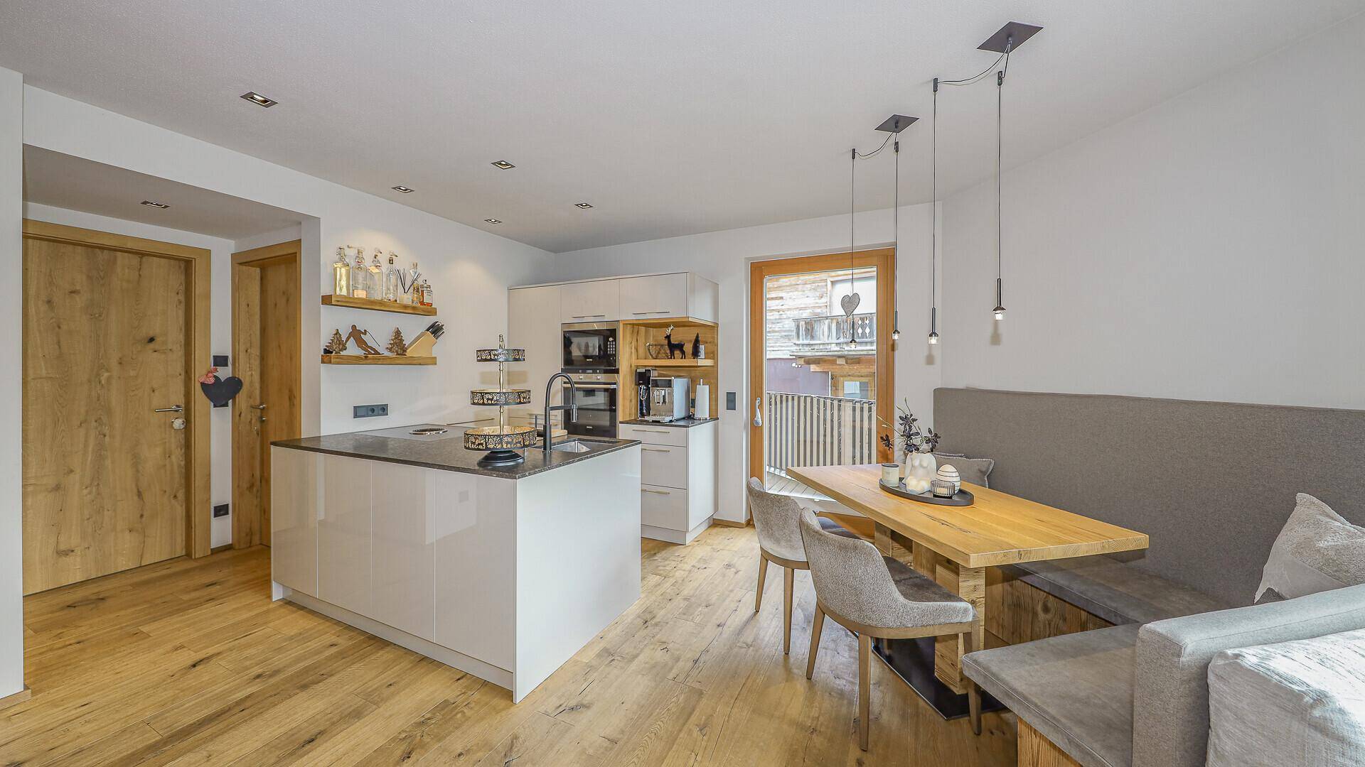 Moderne Küche und Essbereich mit Holztisch und Zugang zum Balkon.