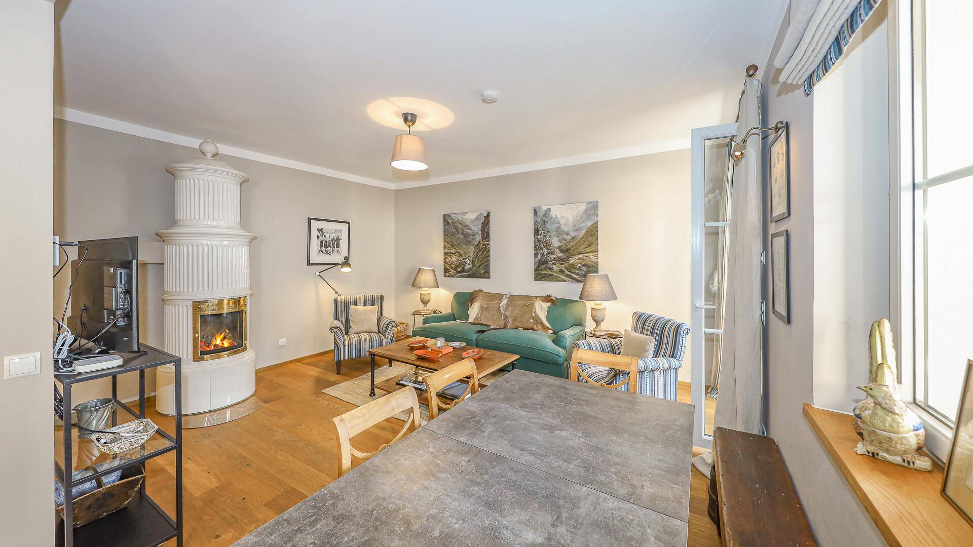 Wohnbereich mit Kaminofen, Holzboden und Zugang zu einem Balkon, ideal für entspannte Abende.