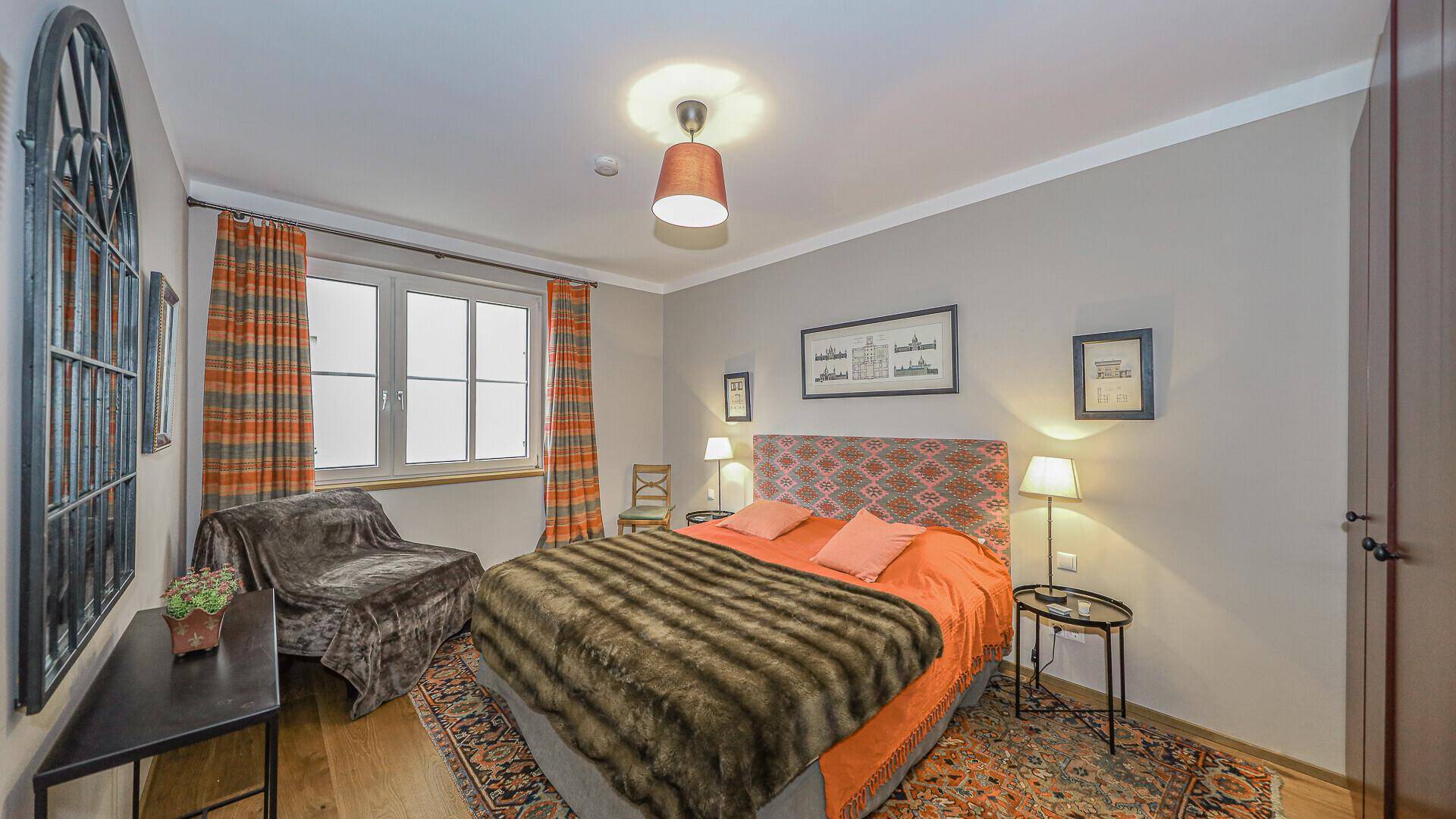 Schlafzimmer mit Doppelbett, Fenster und farbenfroher Dekoration im traditionellen Stil.
