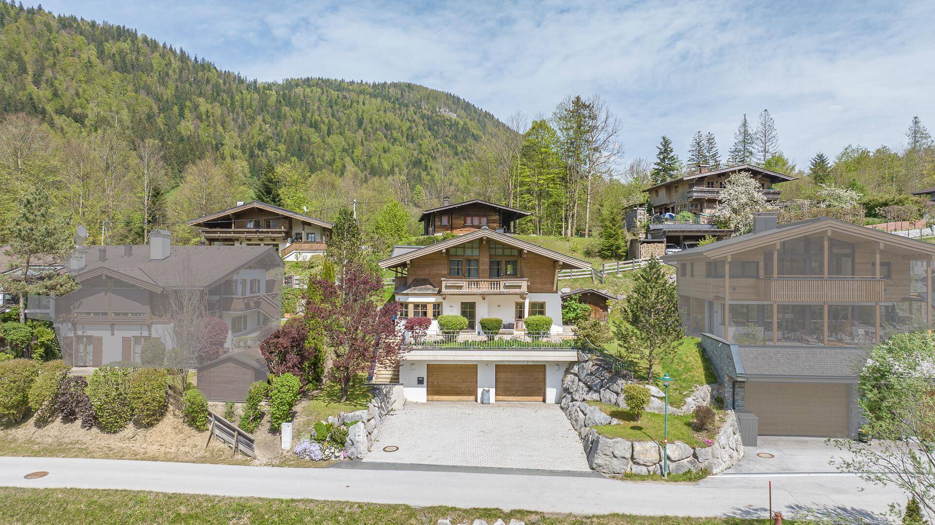 Panoramablick auf das Anwesen mit Doppelgarage, umgeben von üppiger Natur und Bergen.