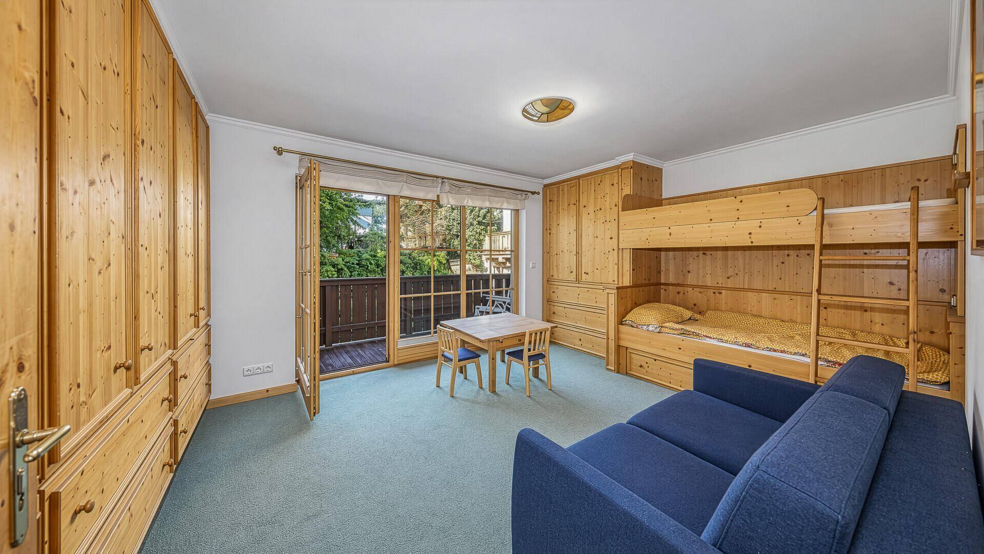 Kinderzimmer mit Etagenbett, kleinem Tisch und direktem Zugang zum Balkon.
