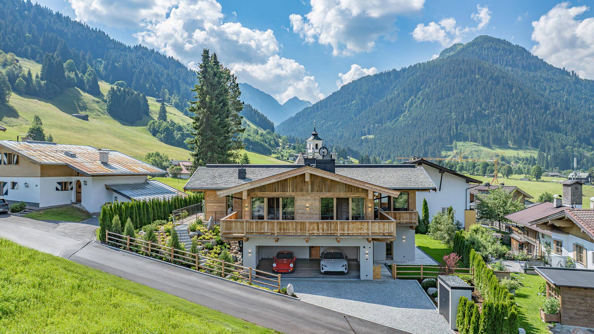 Elegantes Chalet mit Doppelgarage und Balkonen, eingebettet in eine malerische Berglandschaft.