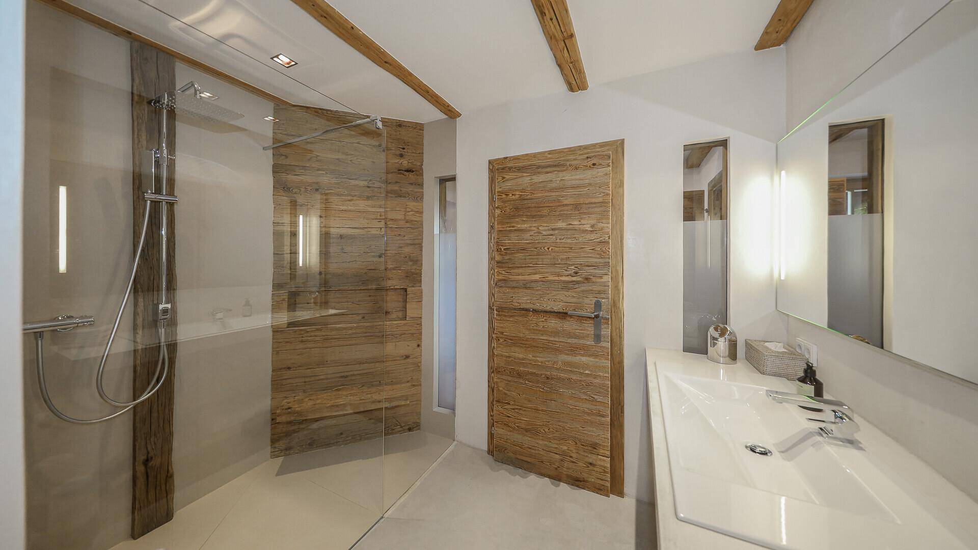 Modernes Badezimmer mit begehbarer Dusche, Holzdetails und Waschbecken mit Spiegel.