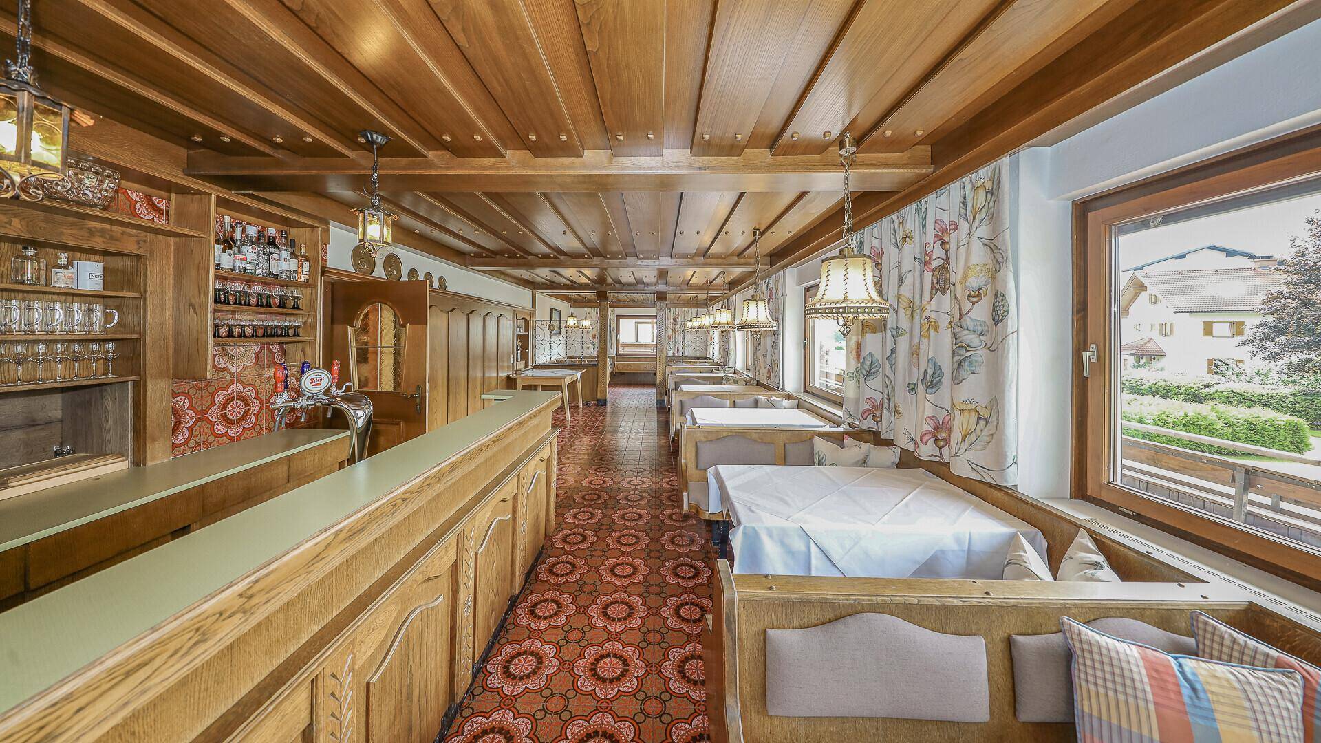 Traditionelles Restaurant mit Holztäfelung, rustikalen Tischen und gemustertem Teppichboden.