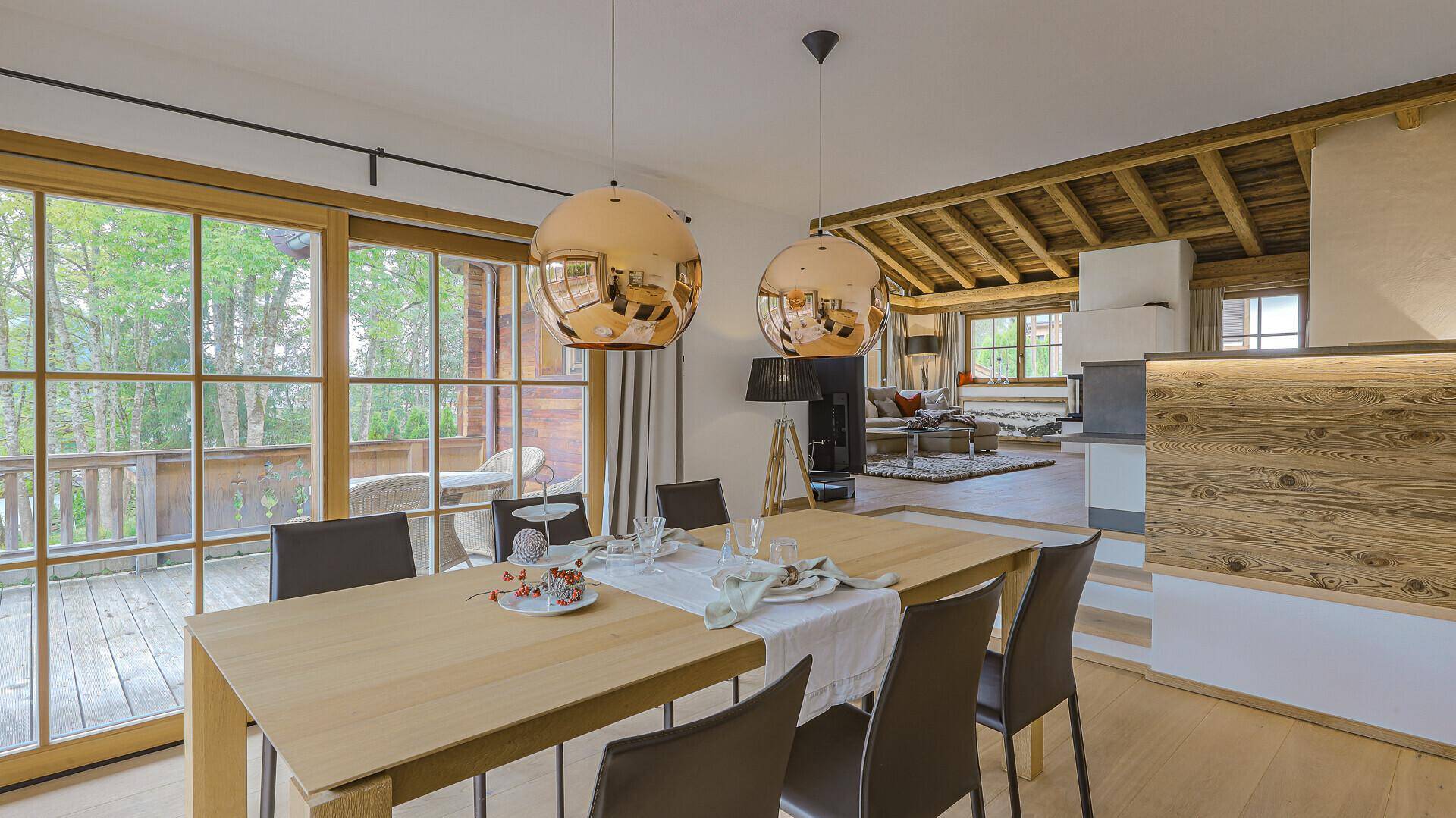 Essbereich mit Holztisch, modernen Leuchten und direktem Zugang zur sonnigen Terrasse.