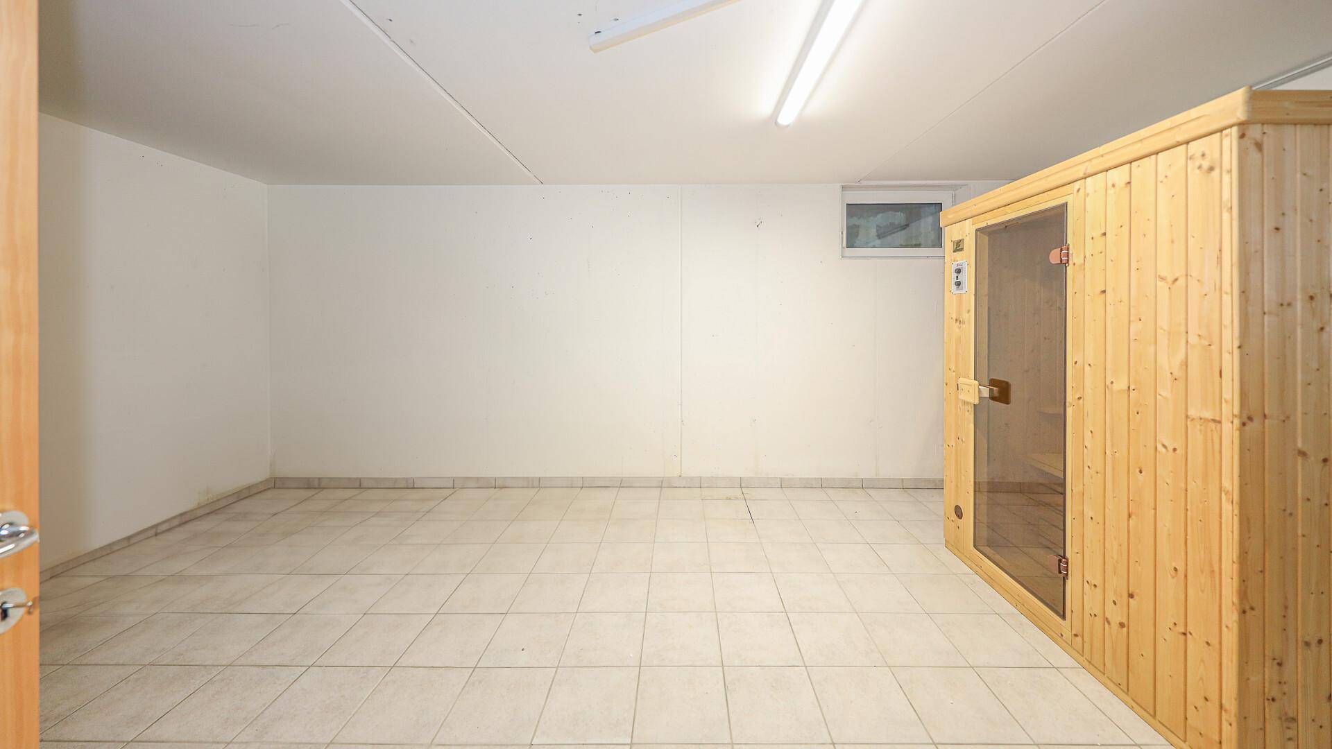Geräumiger Kellerraum mit Fliesenboden und einer integrierten Sauna für Wellnessmomente.
