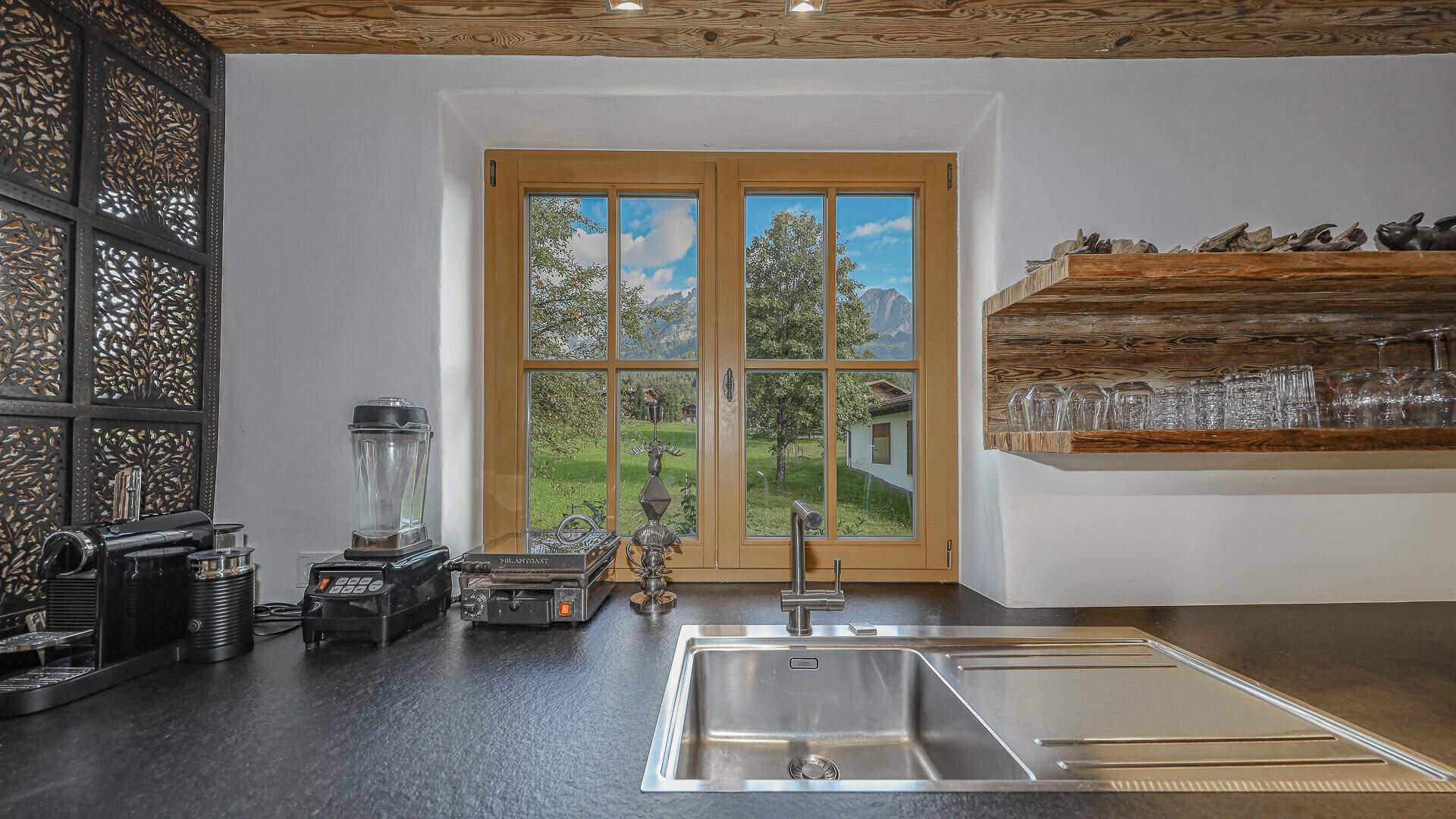 Küchenarbeitsplatte mit Spülbecken und Blick durch das Fenster auf die umliegende Landschaft.