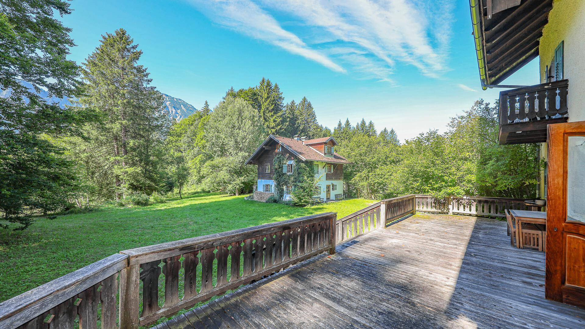 Geräumige Holzterrasse mit Sitzgelegenheiten und Panoramablick auf die Berge und Natur.