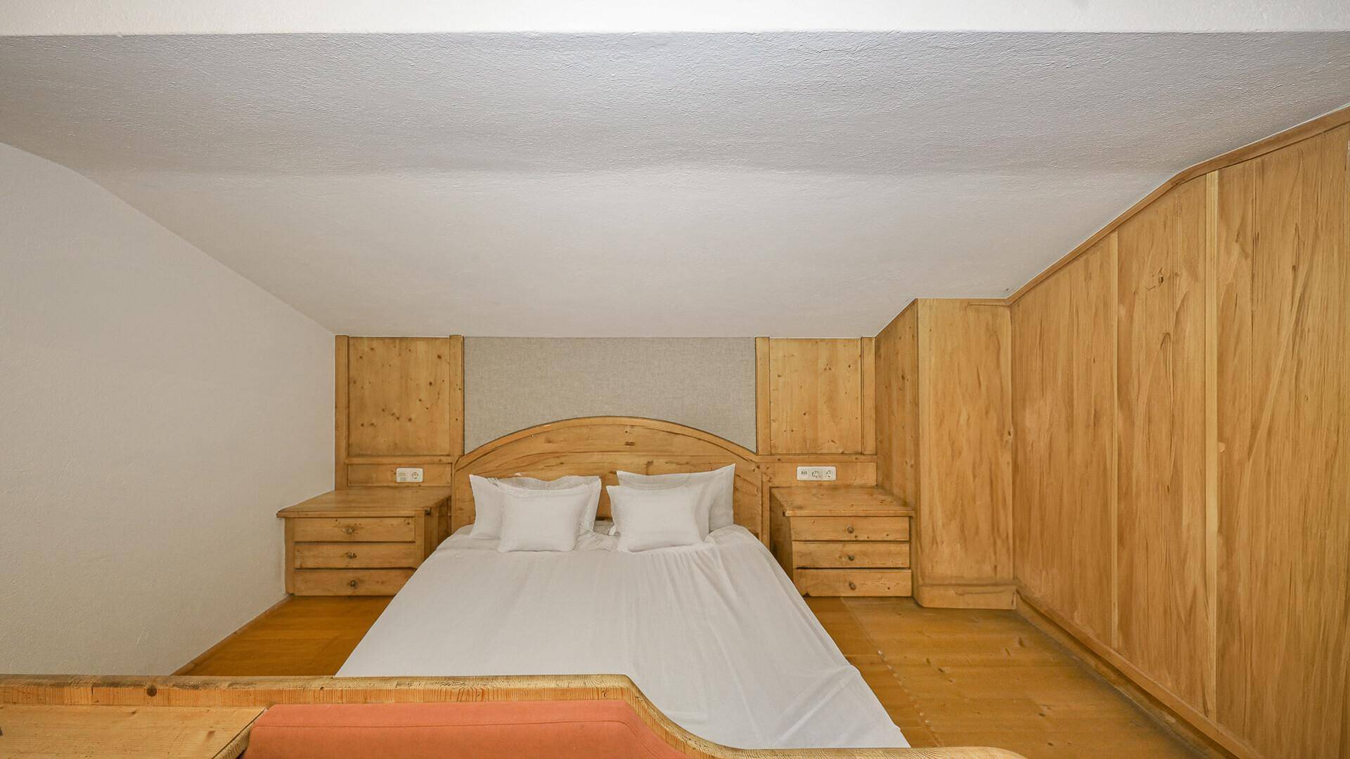 Schlafzimmer im Dachgeschoss mit Holzeinbauten, Doppelbett und gemütlicher Atmosphäre.